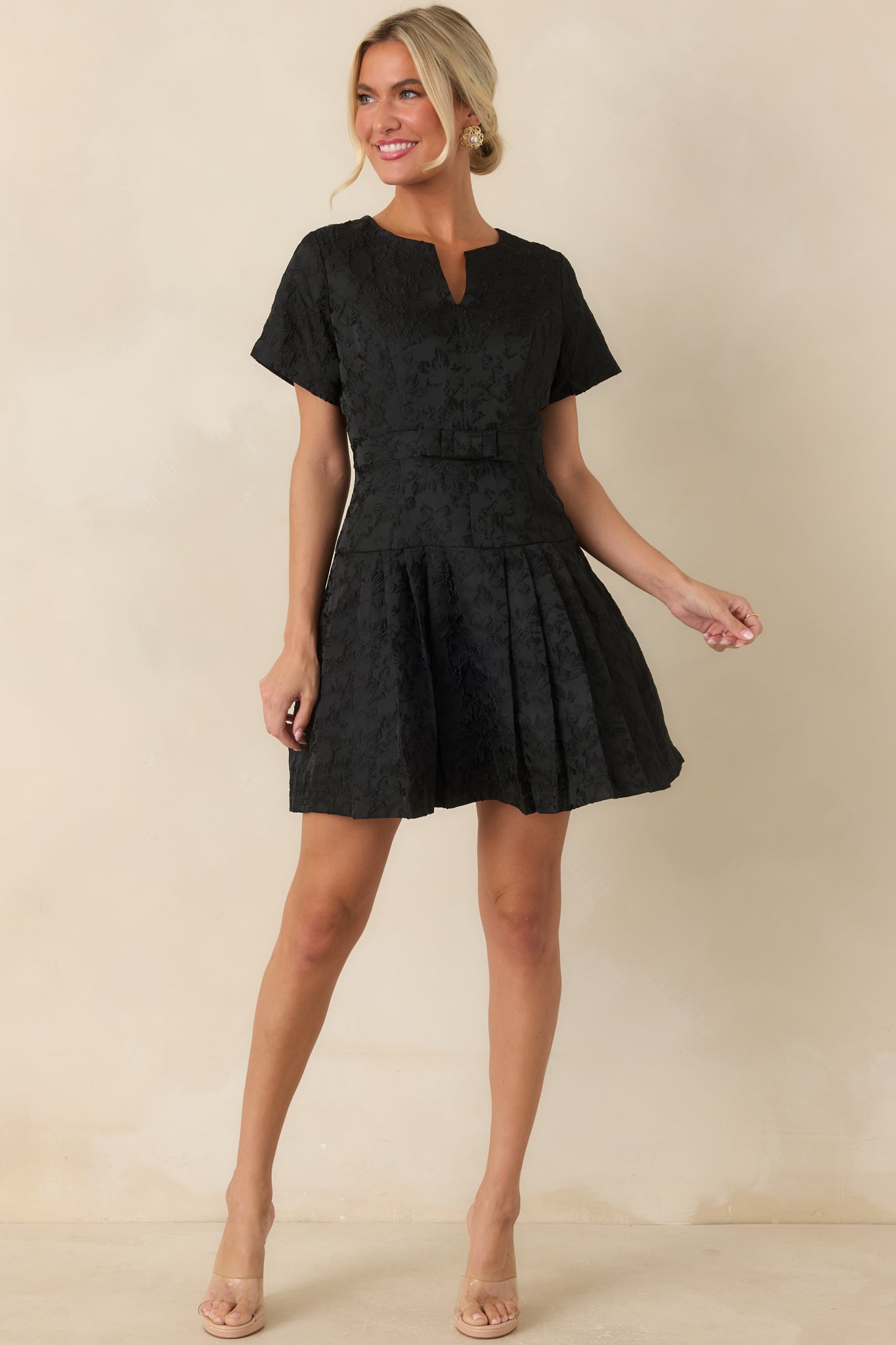 Black fit-and-flare mini dress with short sleeves, textured fabric, and a softly structured skirt.