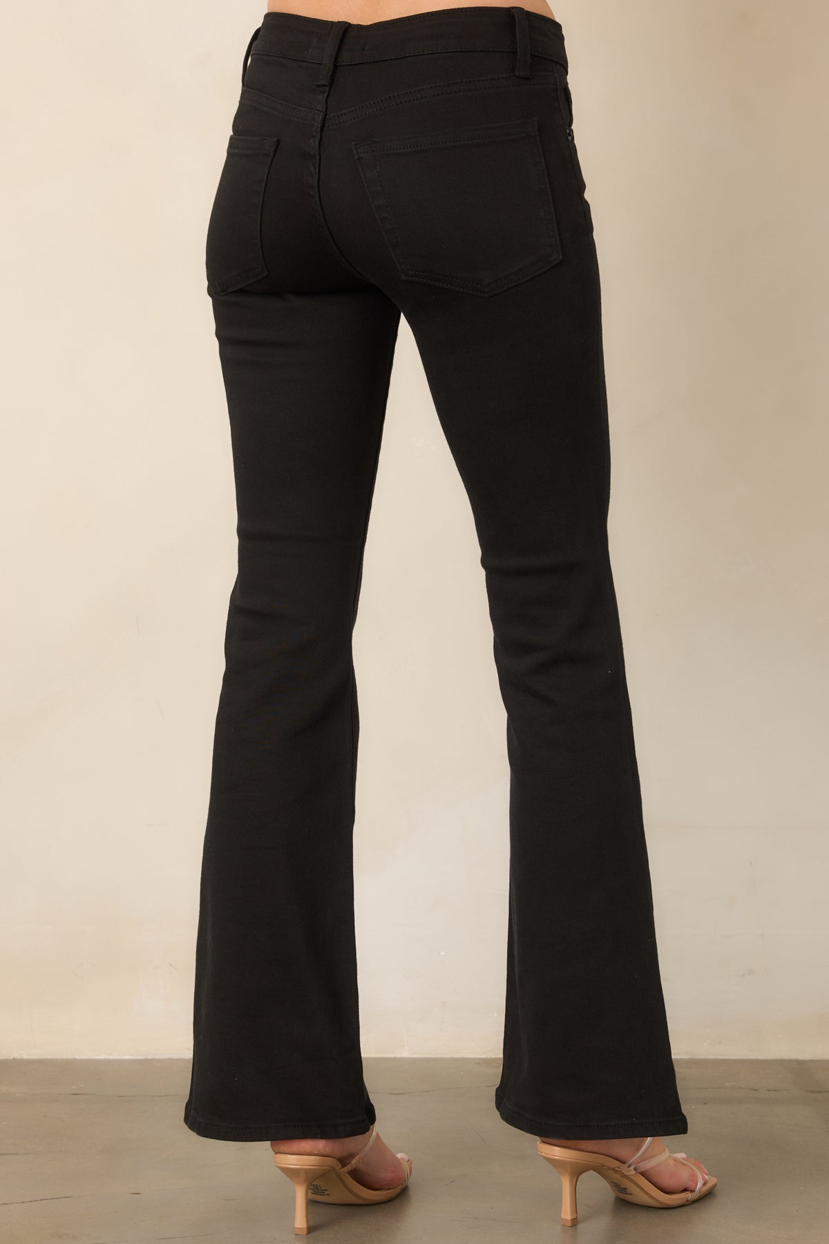 Rear of the black flared jeans showing the fitted hips, five-pocket styling, and clean hems.
