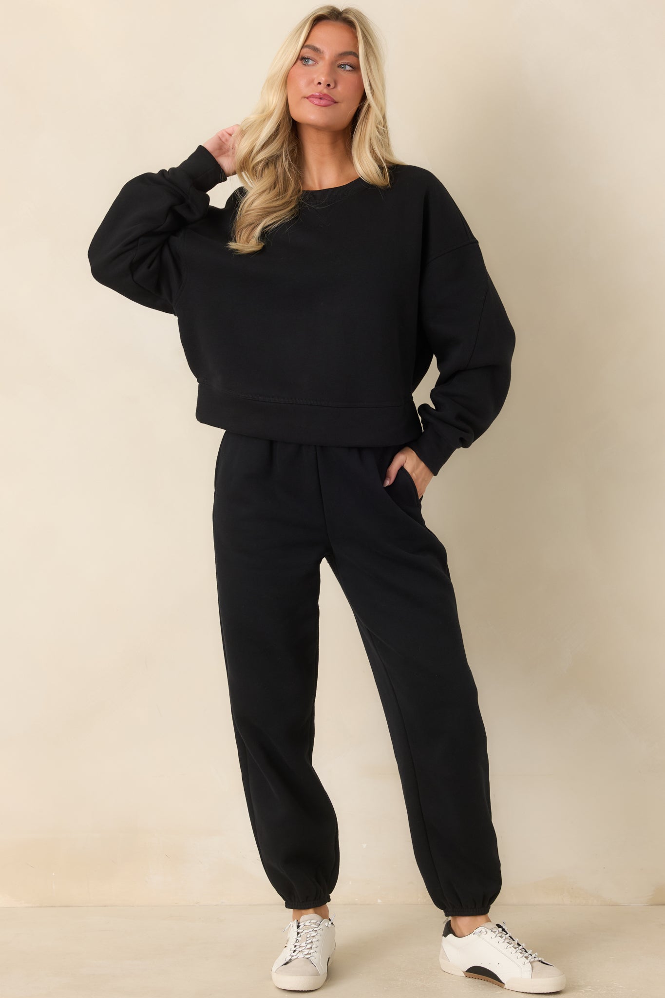 Black fleece sweatshirt featuring dropped shoulders, long sleeves, ribbed detailing, and subtle curved seam accents.