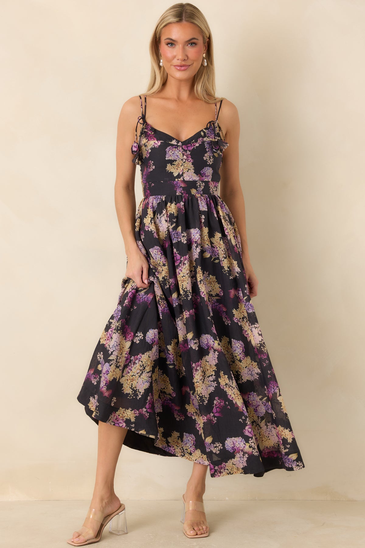 Black floral dress with adjustable shoulder ties, a structured bodice, and a flowing midi-length skirt.