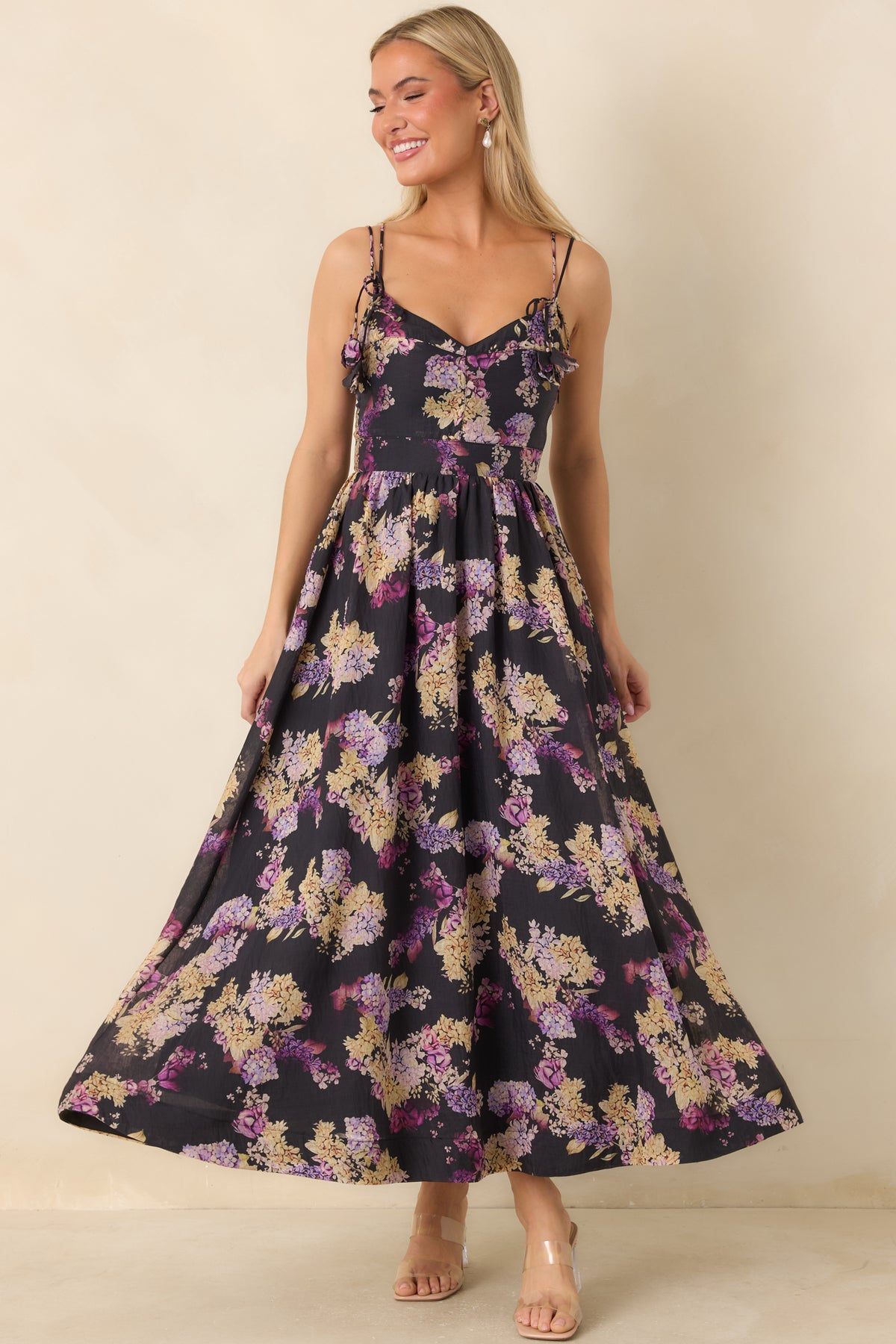 Floral black dress featuring a softly dipped neckline, fitted bodice, and flowing fit-and-flare midi silhouette.
