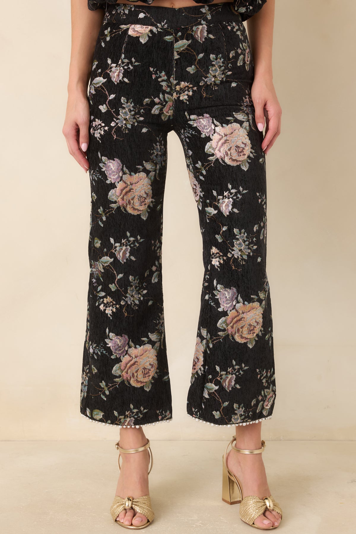Cropped black floral pants with a fitted upper silhouette that flares below the knee.