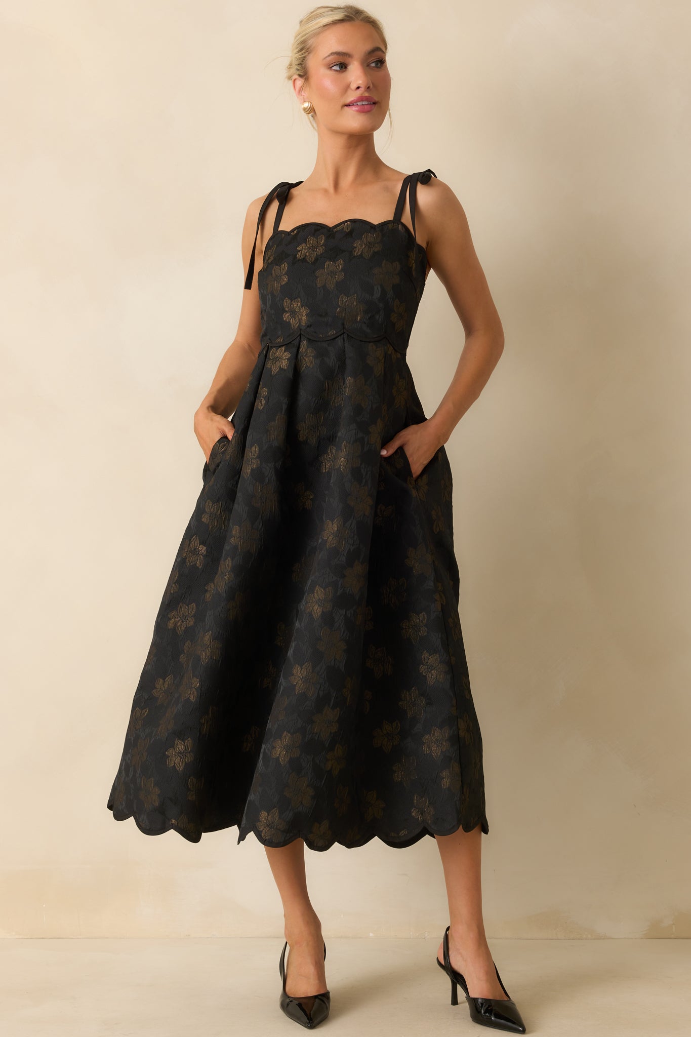 Black floral jacquard dress with midi length, fitted bodice, and decorative gold accents, showing off the scalloped edges.