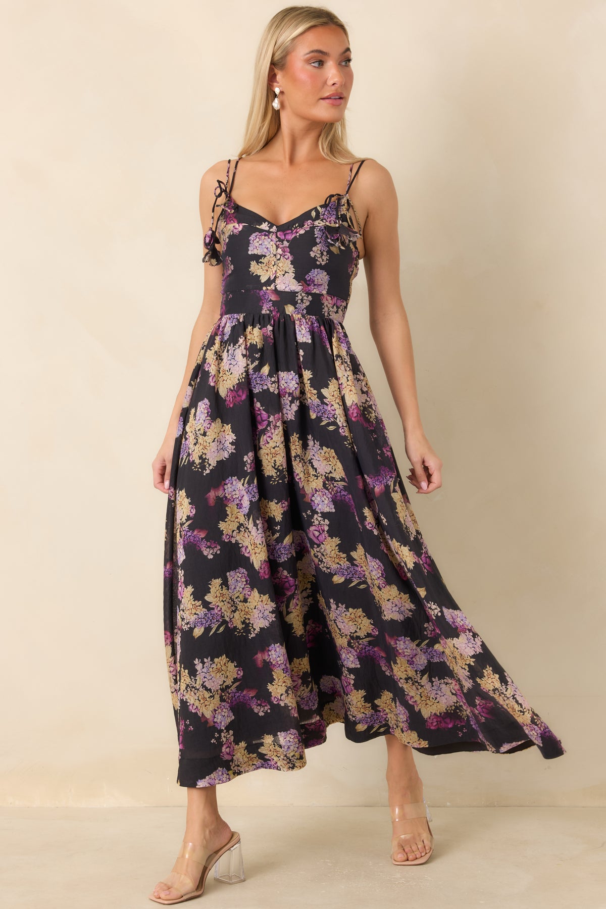Black floral midi dress with pink, lilac, and creamy yellow blooms, adjustable tie straps, and a gathered skirt.