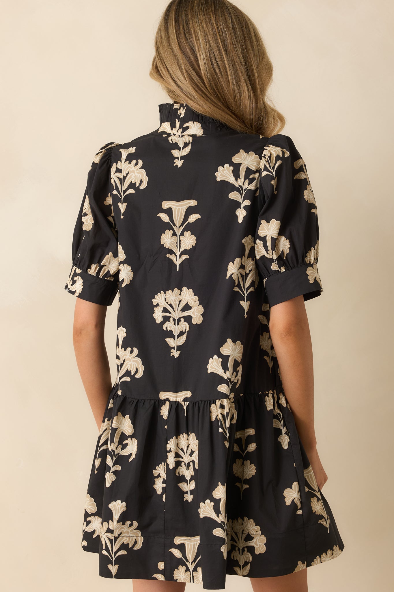 Rear view of the black floral mini dress showing the tiered babydoll silhouette and short puff sleeves.