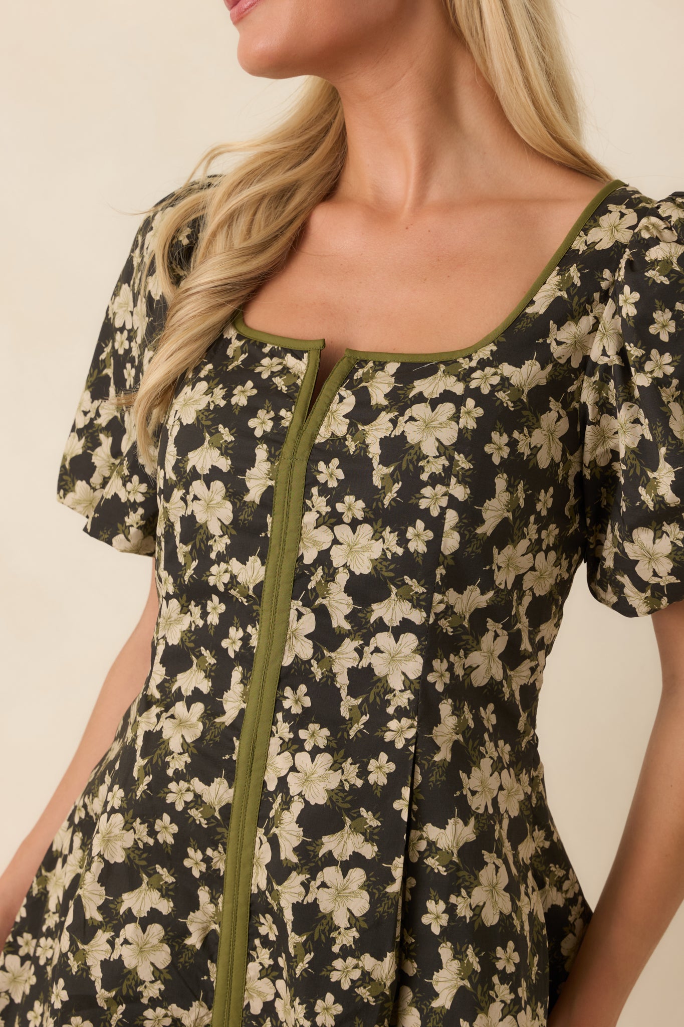 Close-up of the black floral print and olive green trim, highlighting the textured cotton fabric and refined detailing.