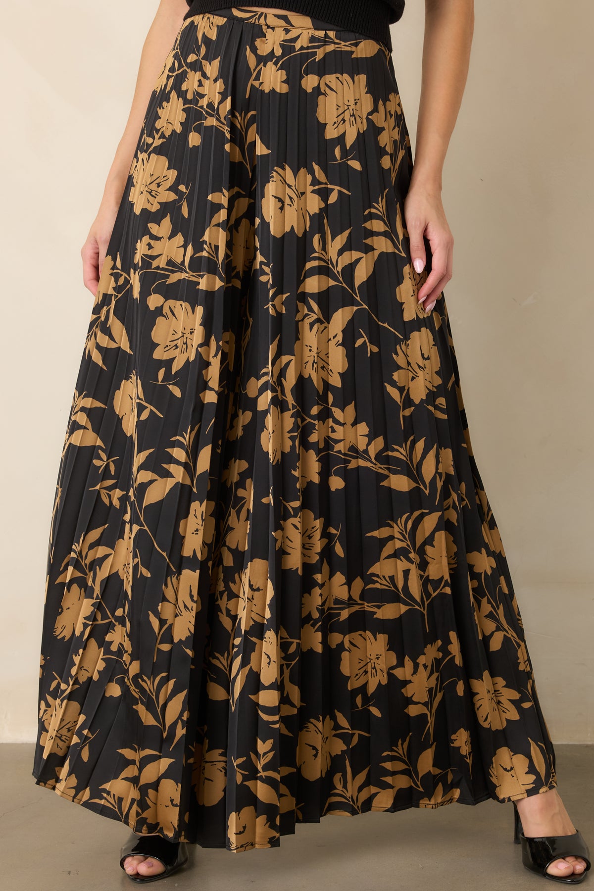 Golden floral details stand out across the black background of these flowing pleated pants.
