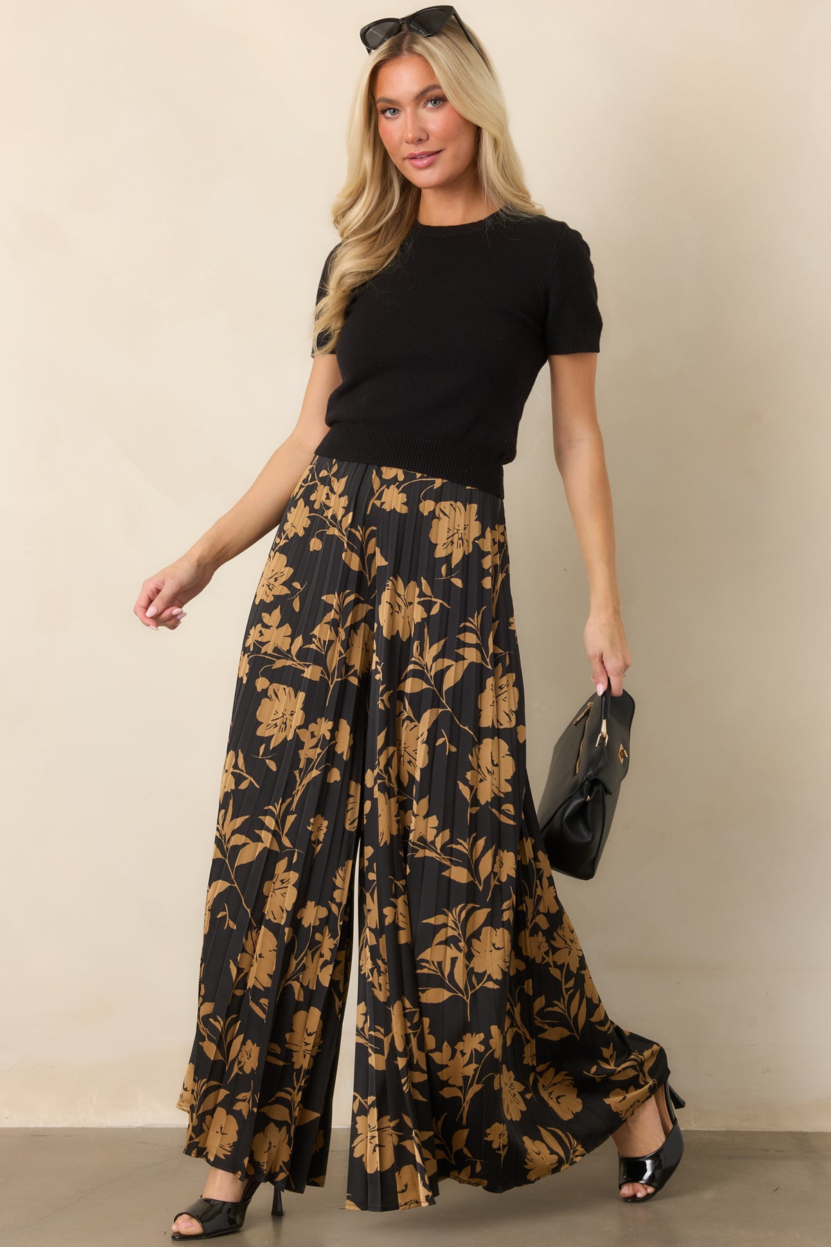 Black pants with golden floral silhouettes, textured pleats, and an elegant wide-leg design.

