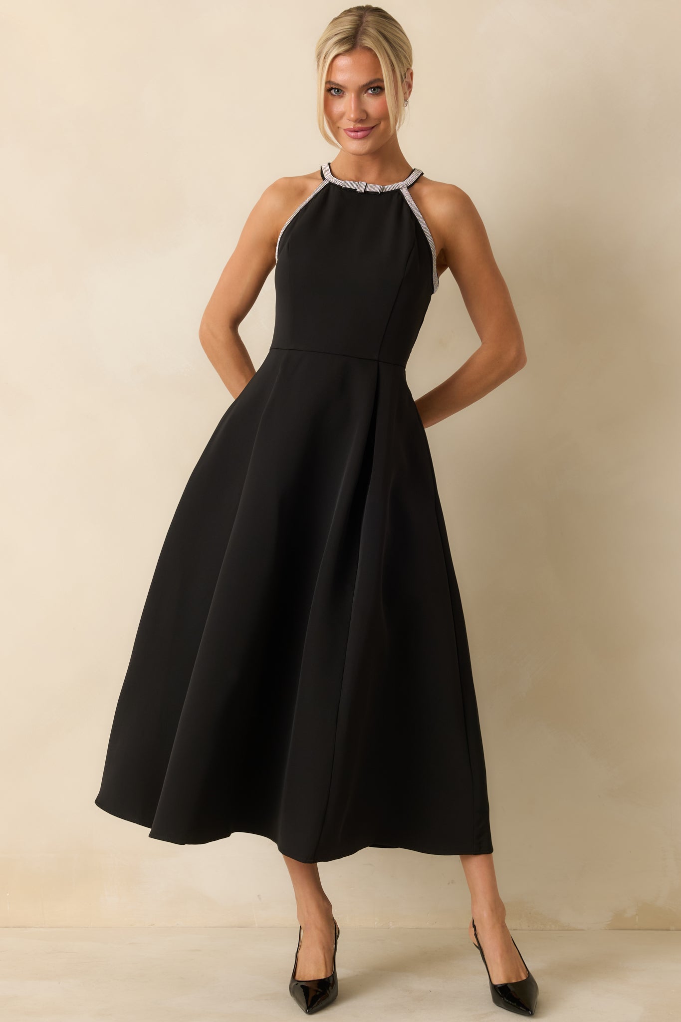 Chic black halter dress with a rhinestone-detailed neckline, fitted waist, and flowy pleated skirt.