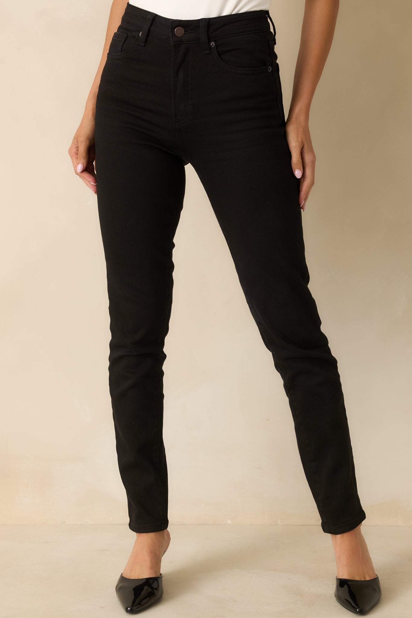View of the black high-rise jeans highlighting the fitted waist and smooth stretch fabric.