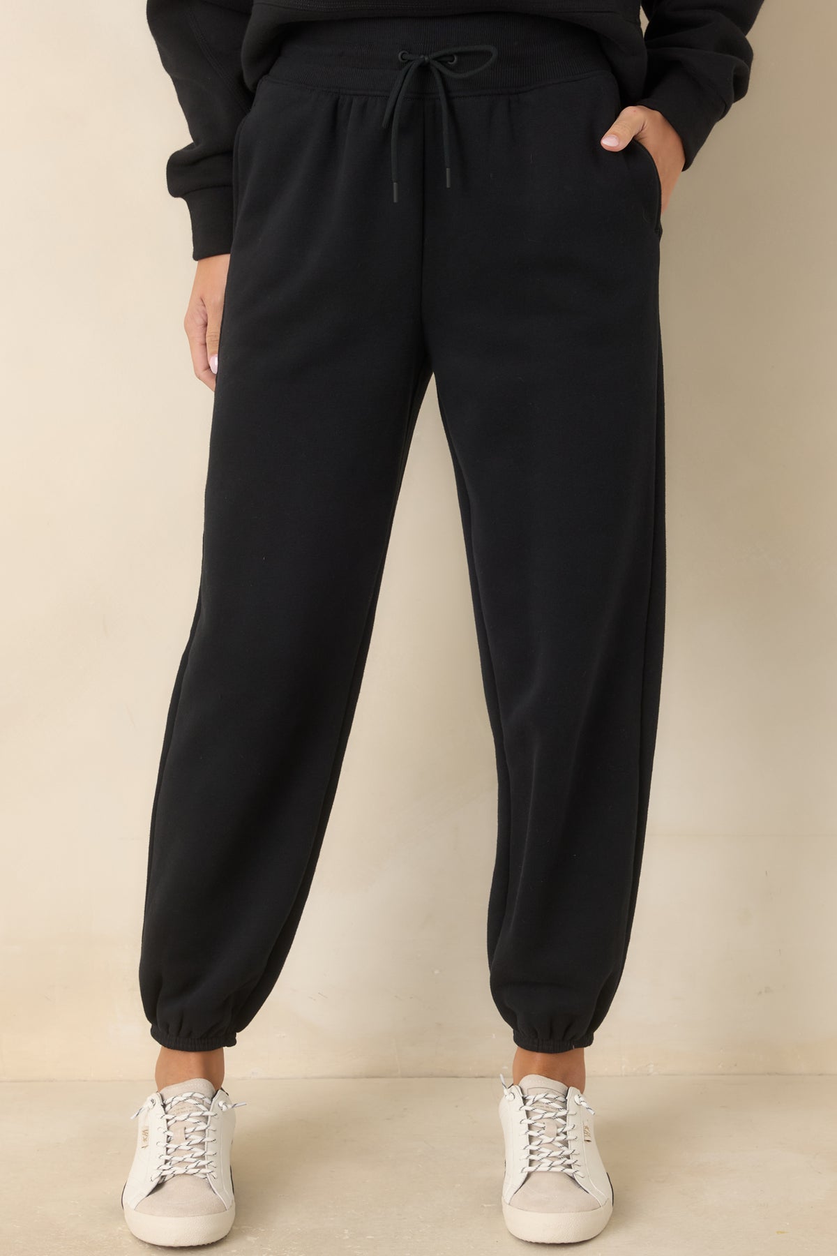 Black joggers highlighting the high-rise ribbed waistband and adjustable drawstring for a secure fit.