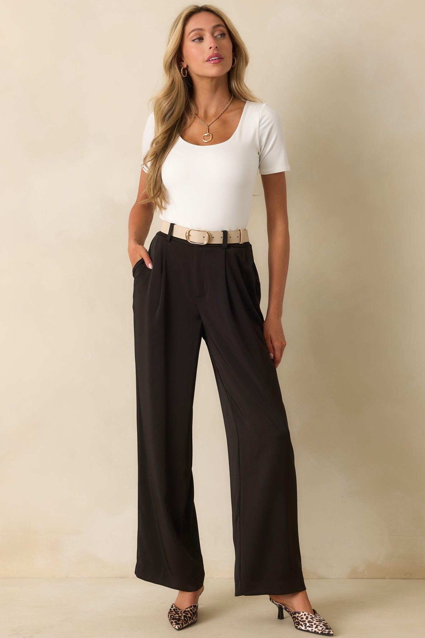 Black high-rise trousers with front pleats, functional side pockets, and a wide-leg silhouette.