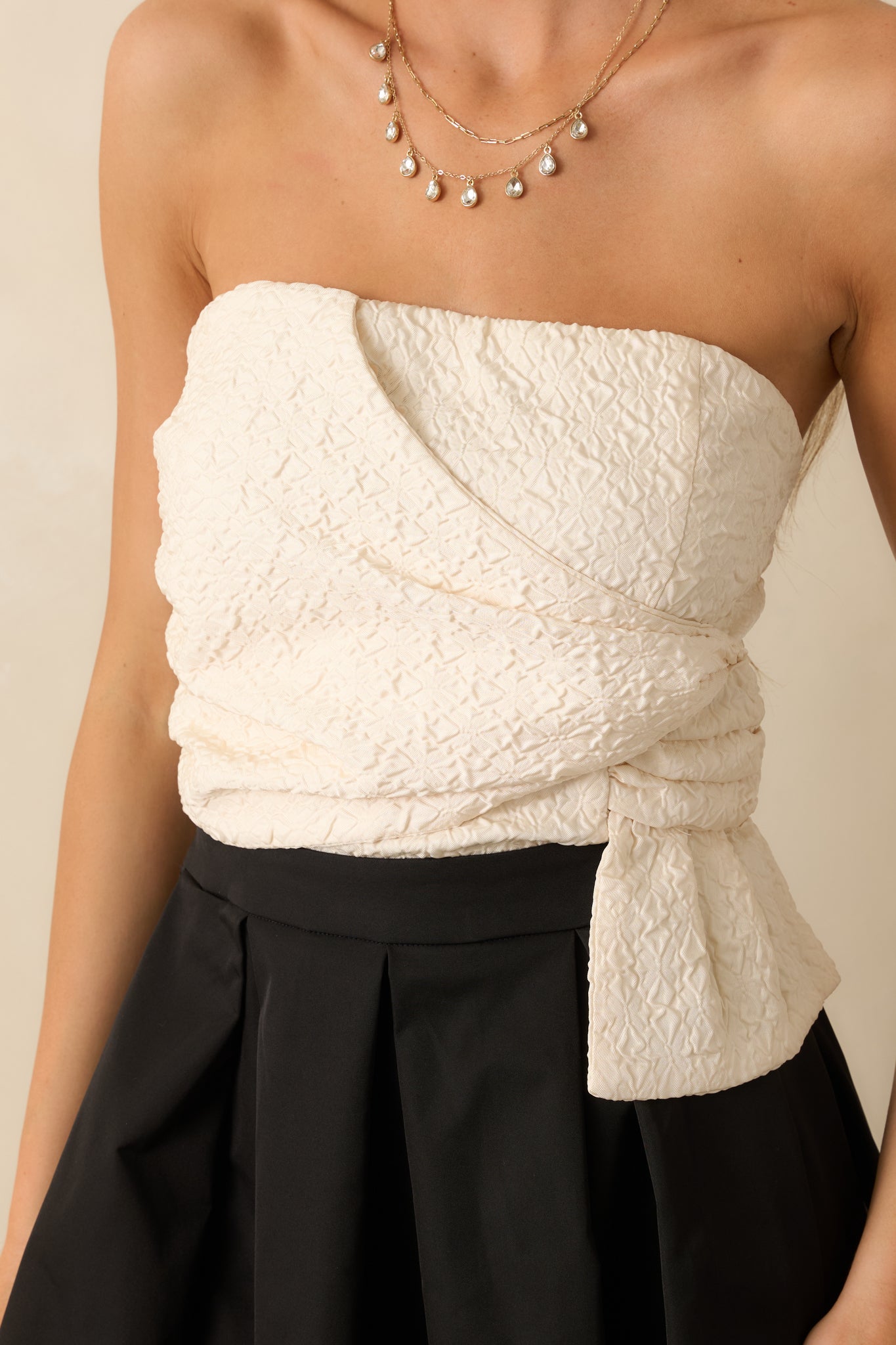 Detailed shot of the black and ivory maxi dress highlighting the textured wrapped bodice, smooth fabric, and structured pleating.