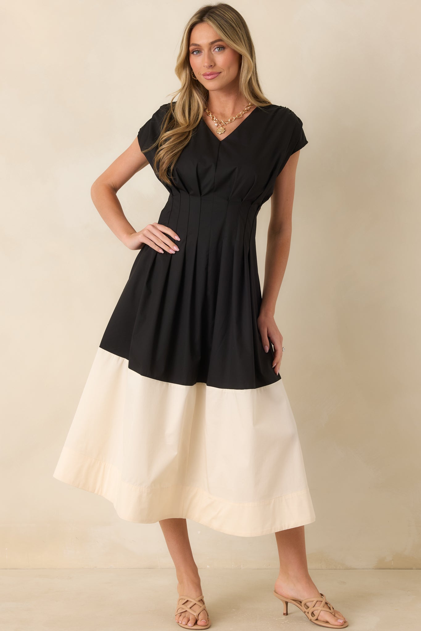 Black and ivory midi dress crafted from a cotton blend with a flattering V-neckline, pleated bodice, and cap-style sleeves.