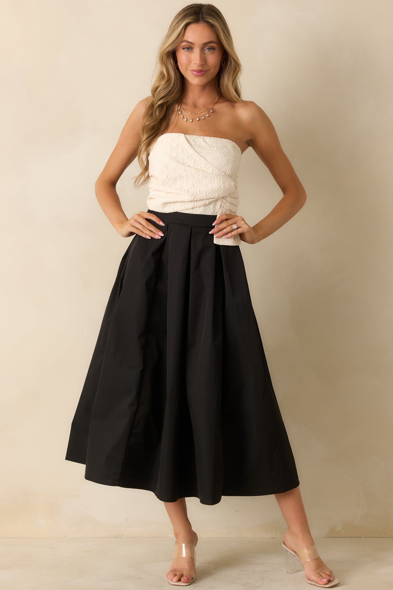 Black and ivory strapless maxi dress with a textured ivory wrapped bodice, high waist, and full A-line skirt with structured pleating.