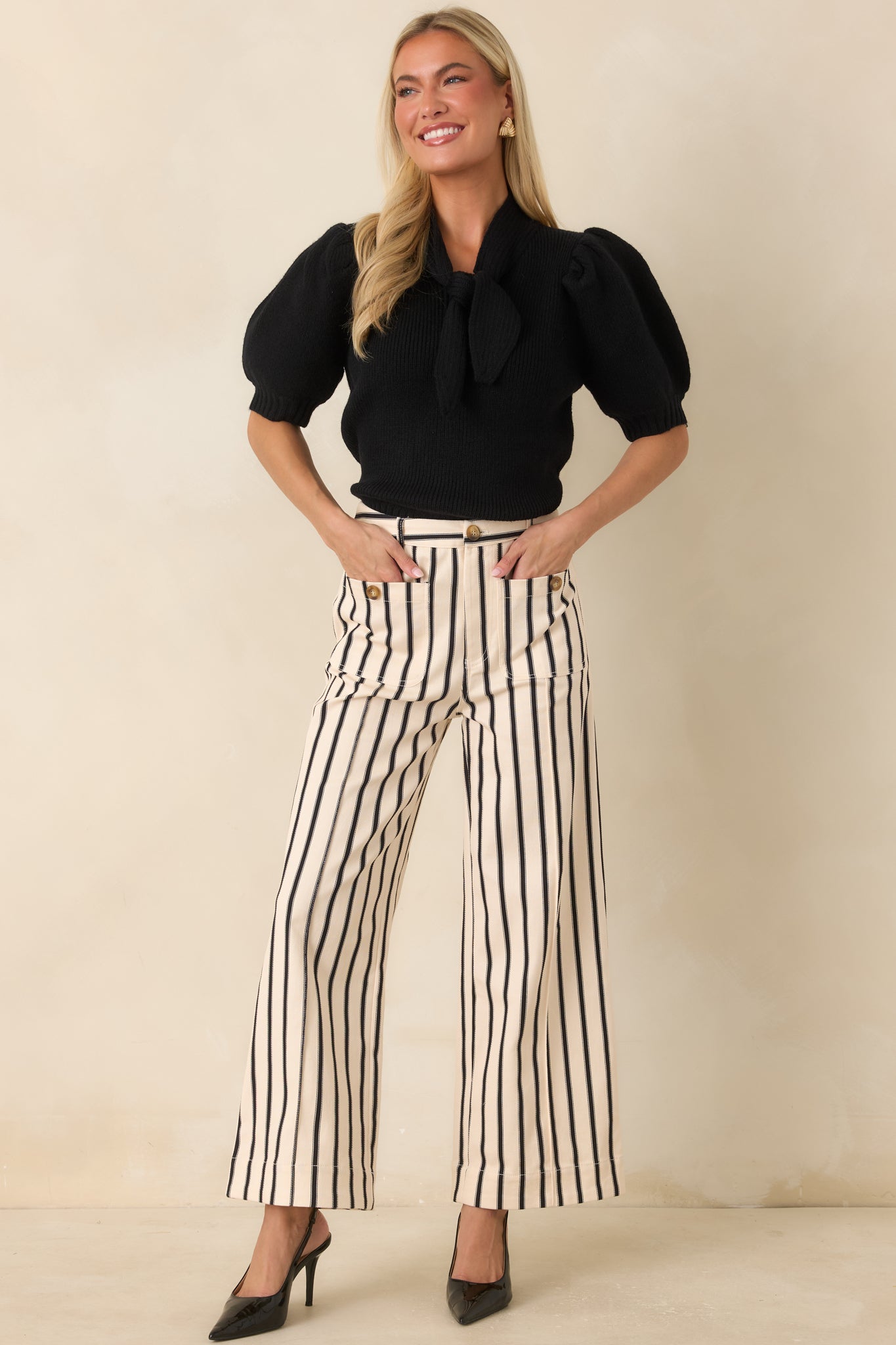 Black and ivory striped high-rise pants featuring a wide-leg silhouette, oversized front patch pockets, and decorative button accents.
