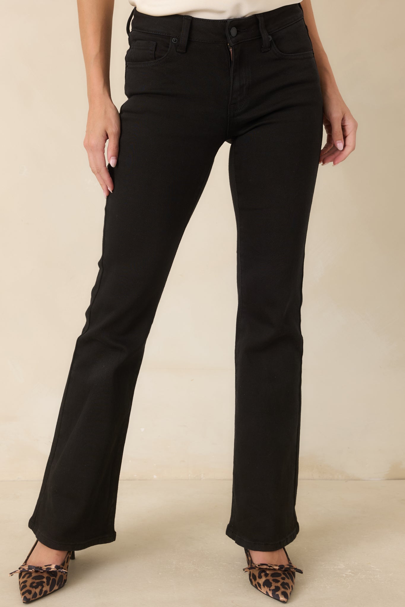 The front of these black jeans highlights the mid-rise waistband, belt loops, and button closure.