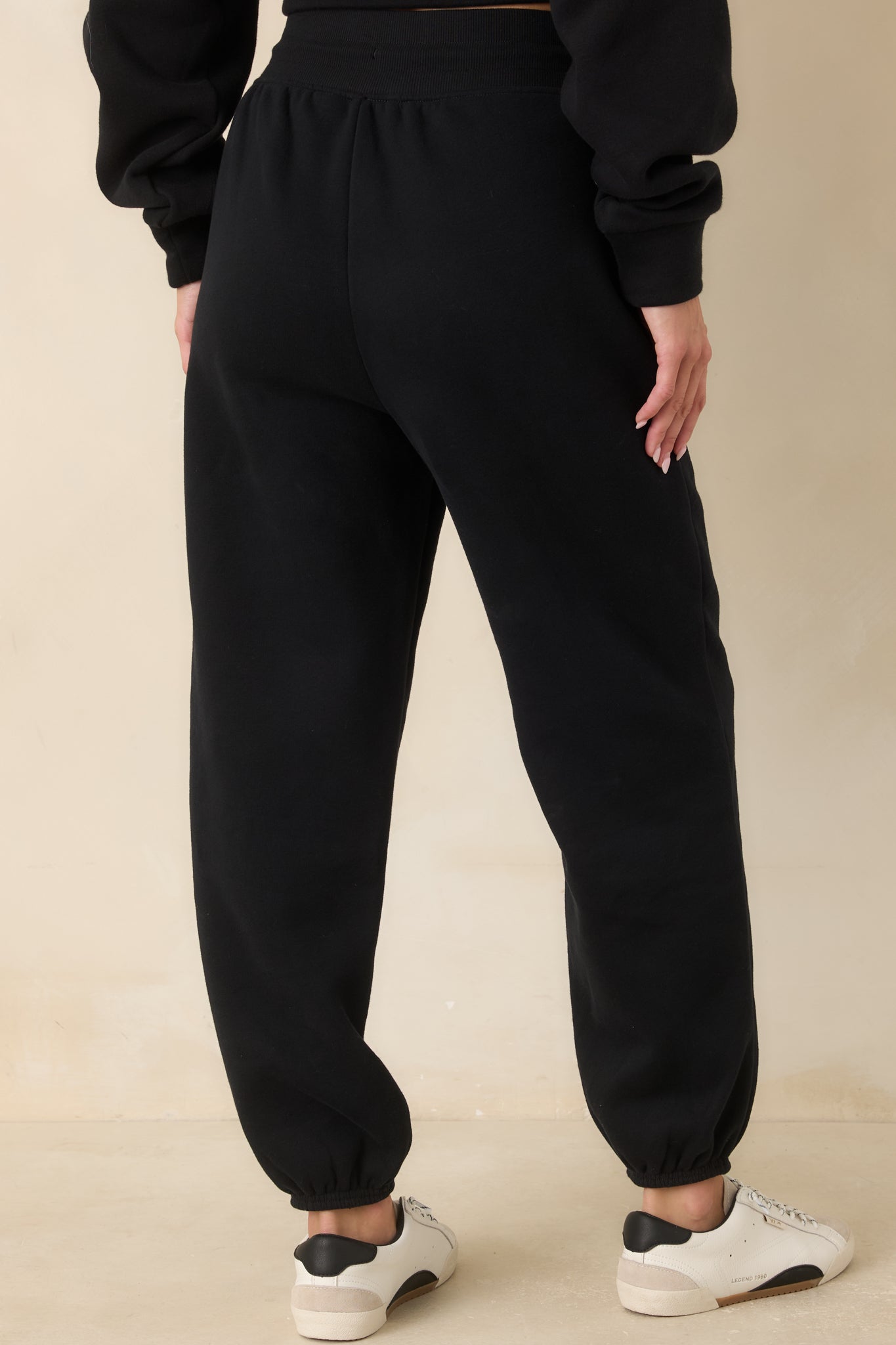 Rear view of the black joggers featuring a relaxed tapered silhouette, elasticized cuffs, and clean back design.