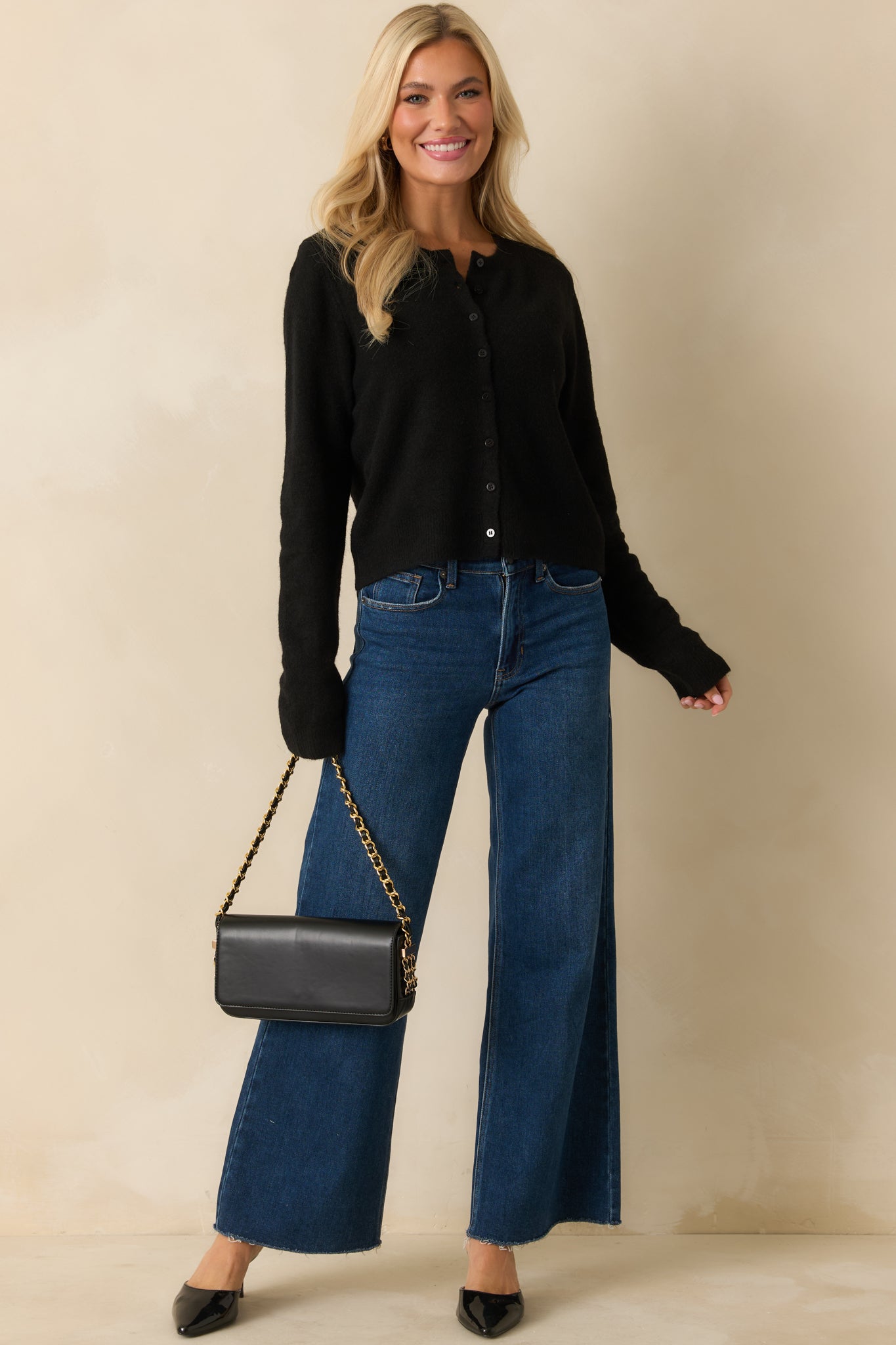 Black knit cardigan featuring its round neckline, front buttons, and easy drape framed by ribbed trim.