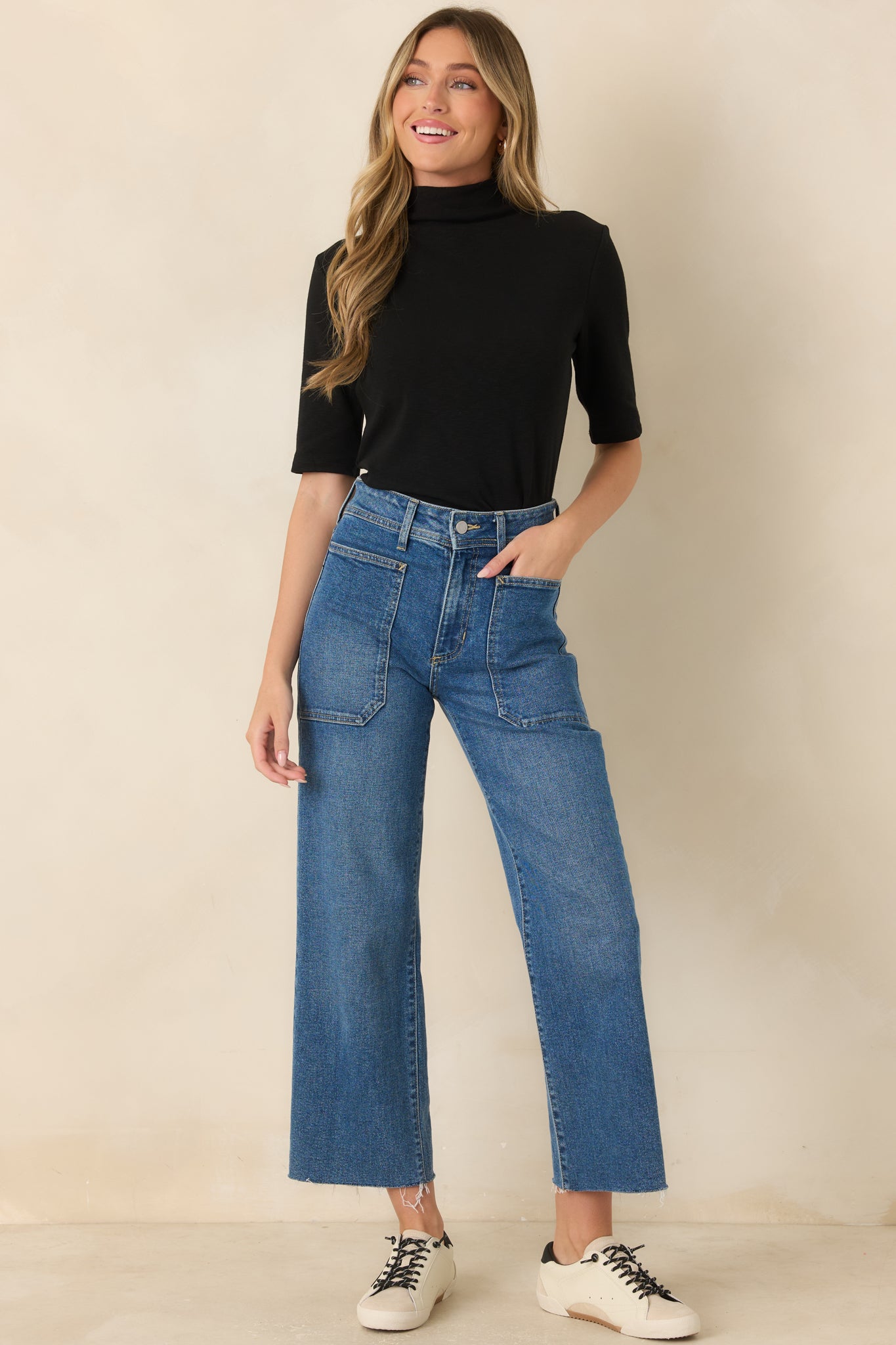 Black knit top featuring a refined mock neckline, elbow-length sleeves, and a gently fitted silhouette with a smooth polished finish.