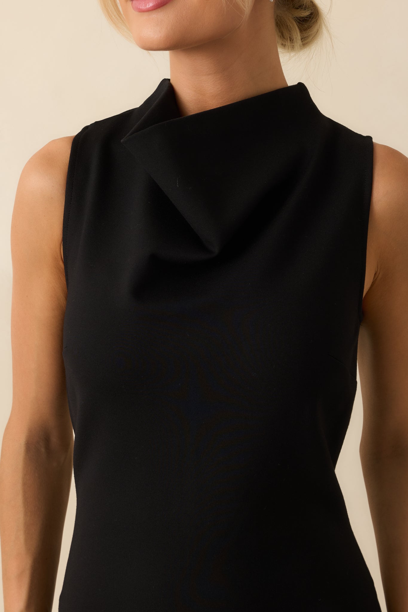 Detailed view of the black midi dress highlighting the smooth ponte fabric, high neckline, and precise tailoring of the bodycon silhouette.