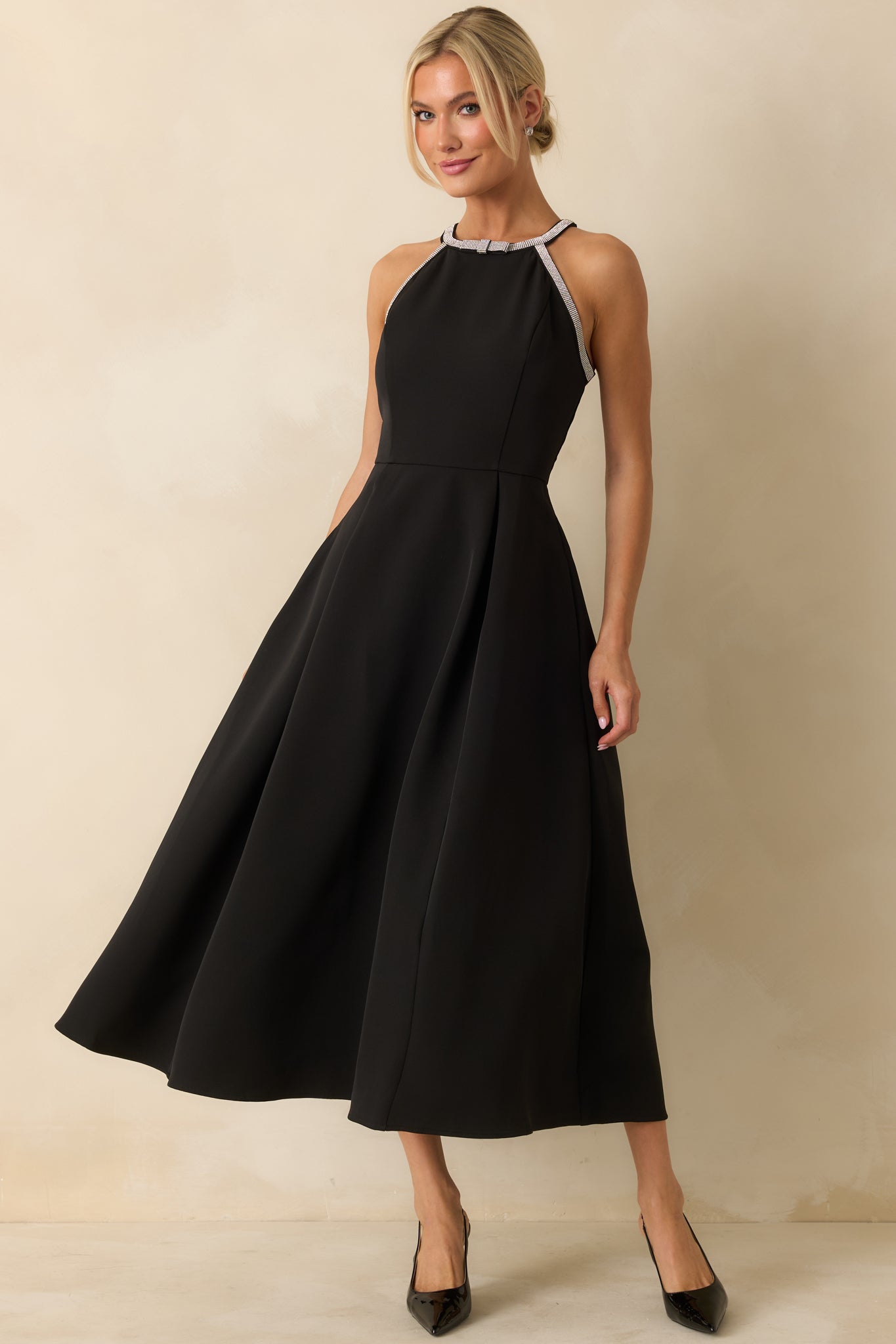 Elegant black midi dress featuring a halter neckline with rhinestone trim and a softly pleated A-line silhouette.