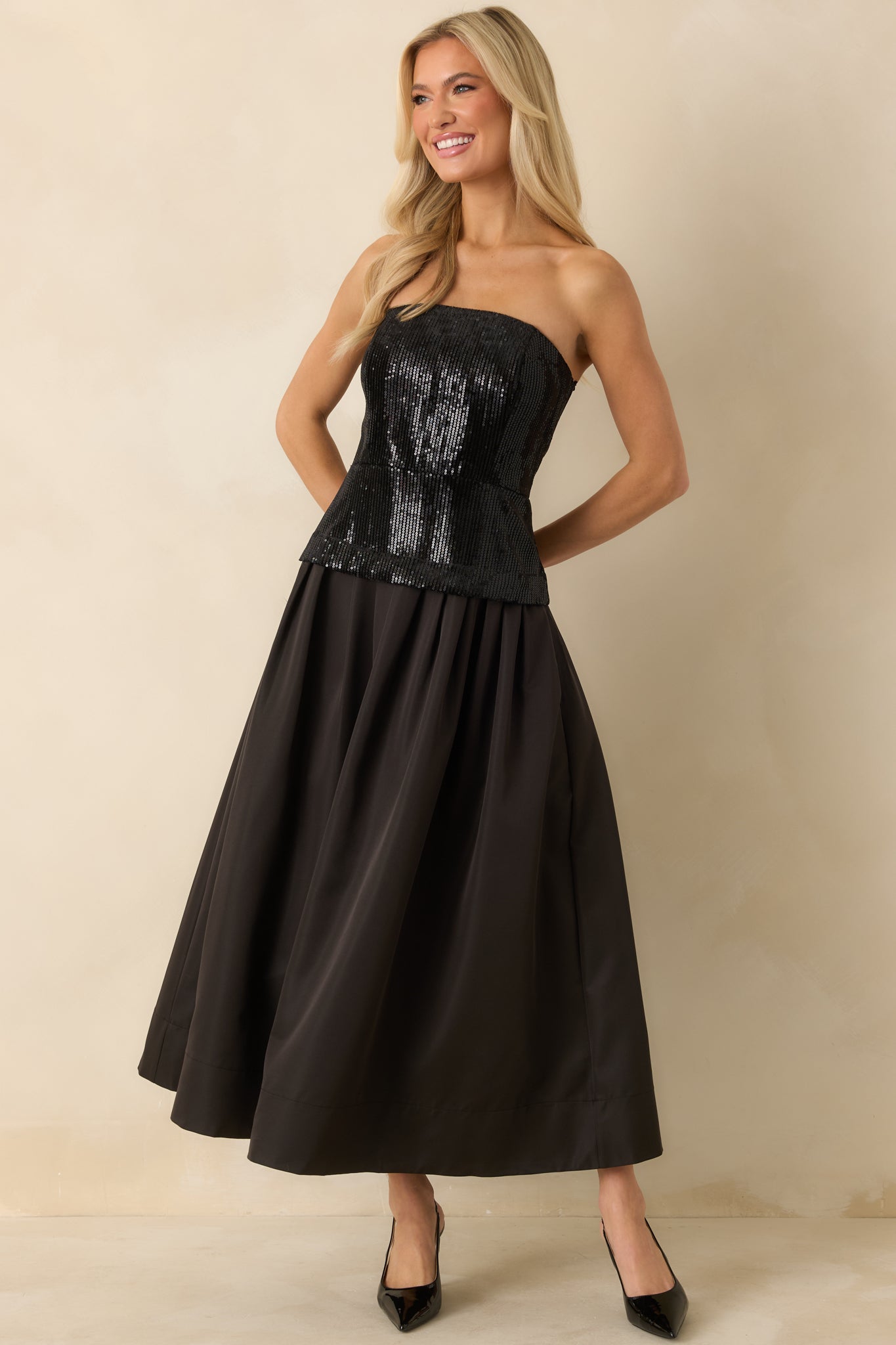 Black midi dress with a strapless sequin bodice and structured boning above a voluminous pleated satin skirt.