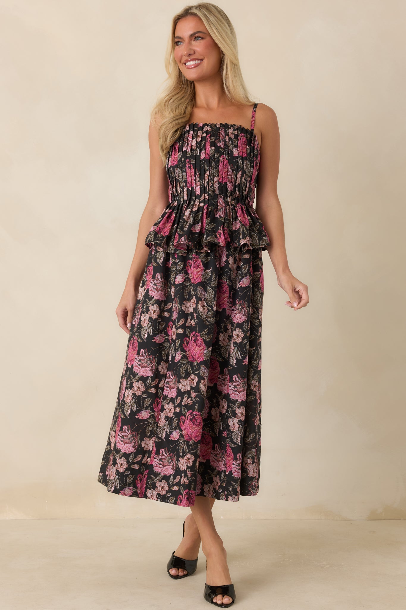Black midi dress featuring an allover pink floral print, slender shoulder straps, and a flowing silhouette.