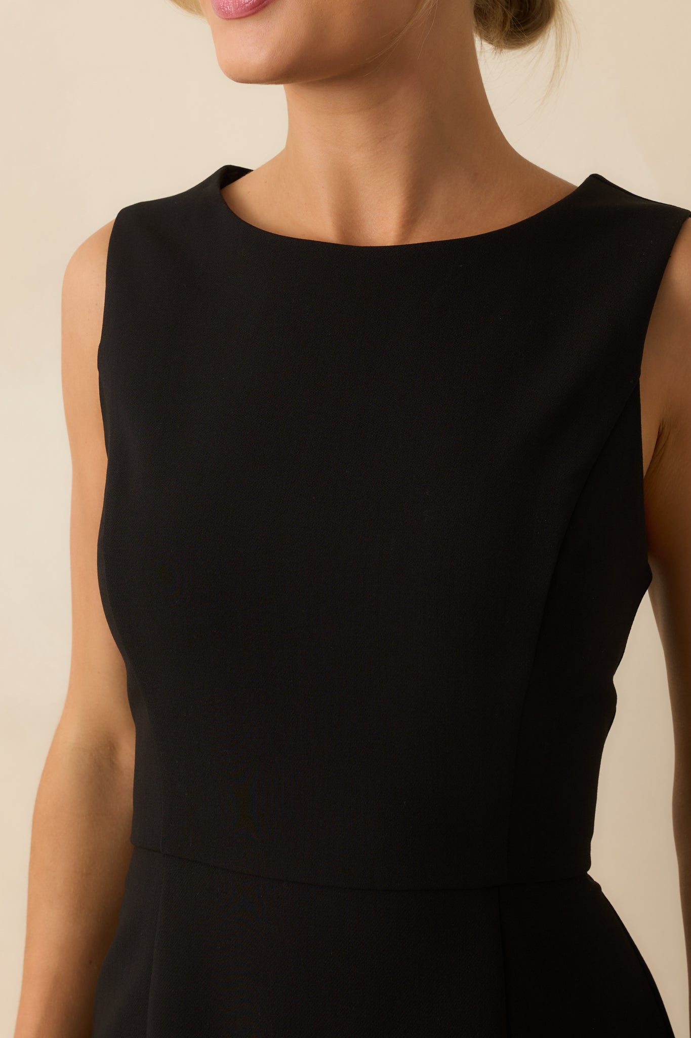Close-up of the ivory pleated ruffle hem and fabric texture on the black mini dress.