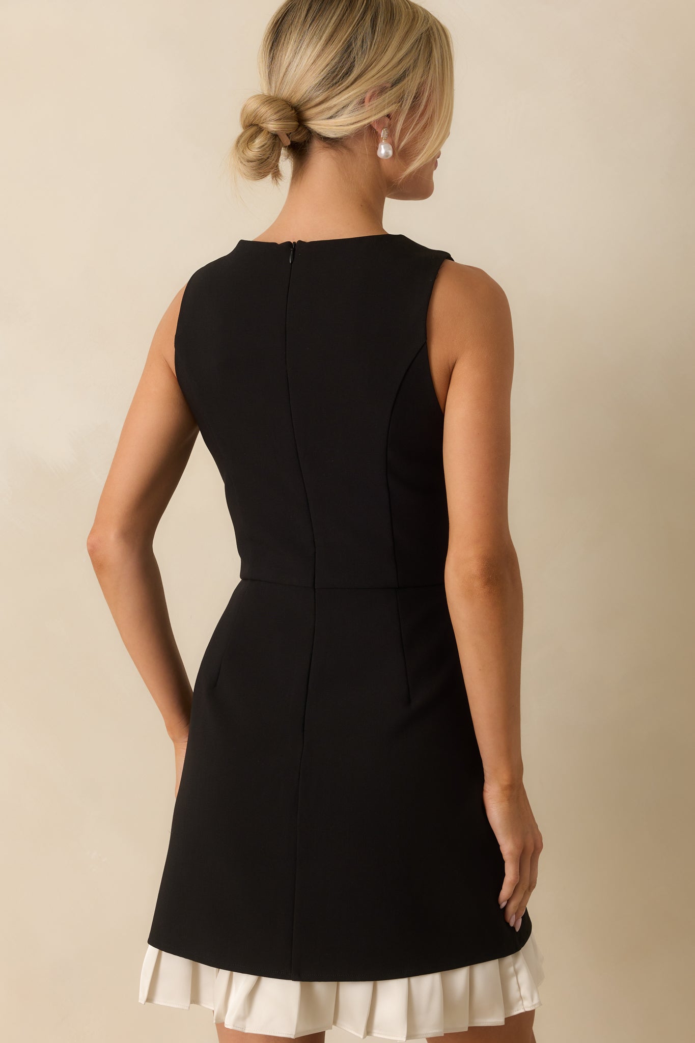 Rear view of the black mini dress showing the concealed back zipper and structured silhouette.