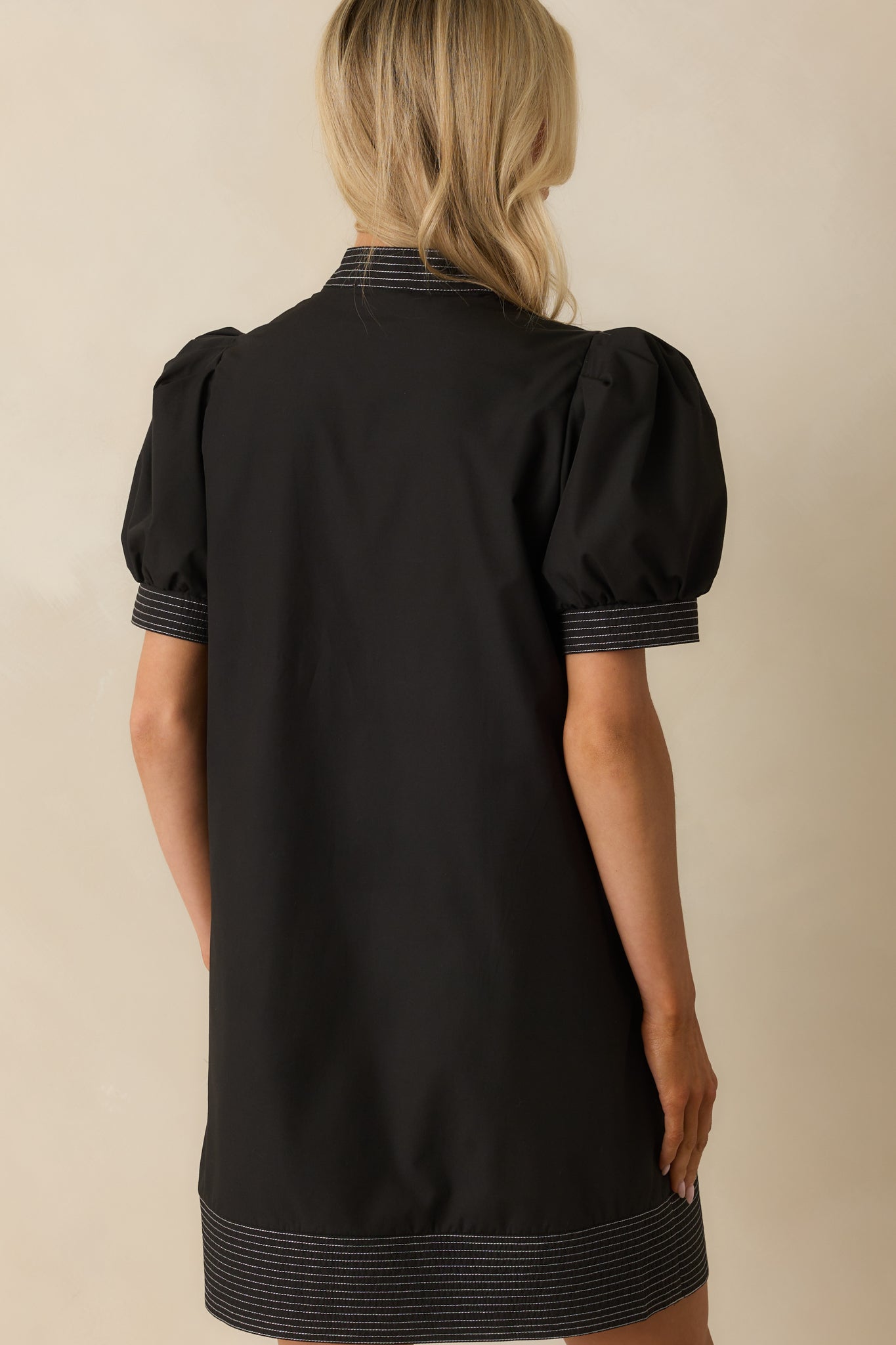 Rear view of the black mini dress with contrast stitching continuing throughout.