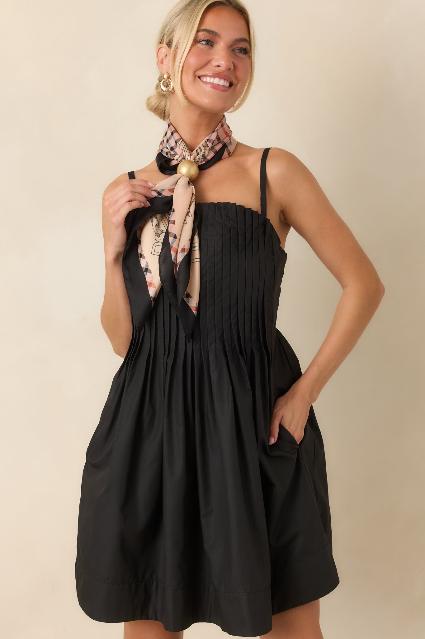 Close-up view of the black mini dress highlighting the pleated texture and soft gathered skirt detail.