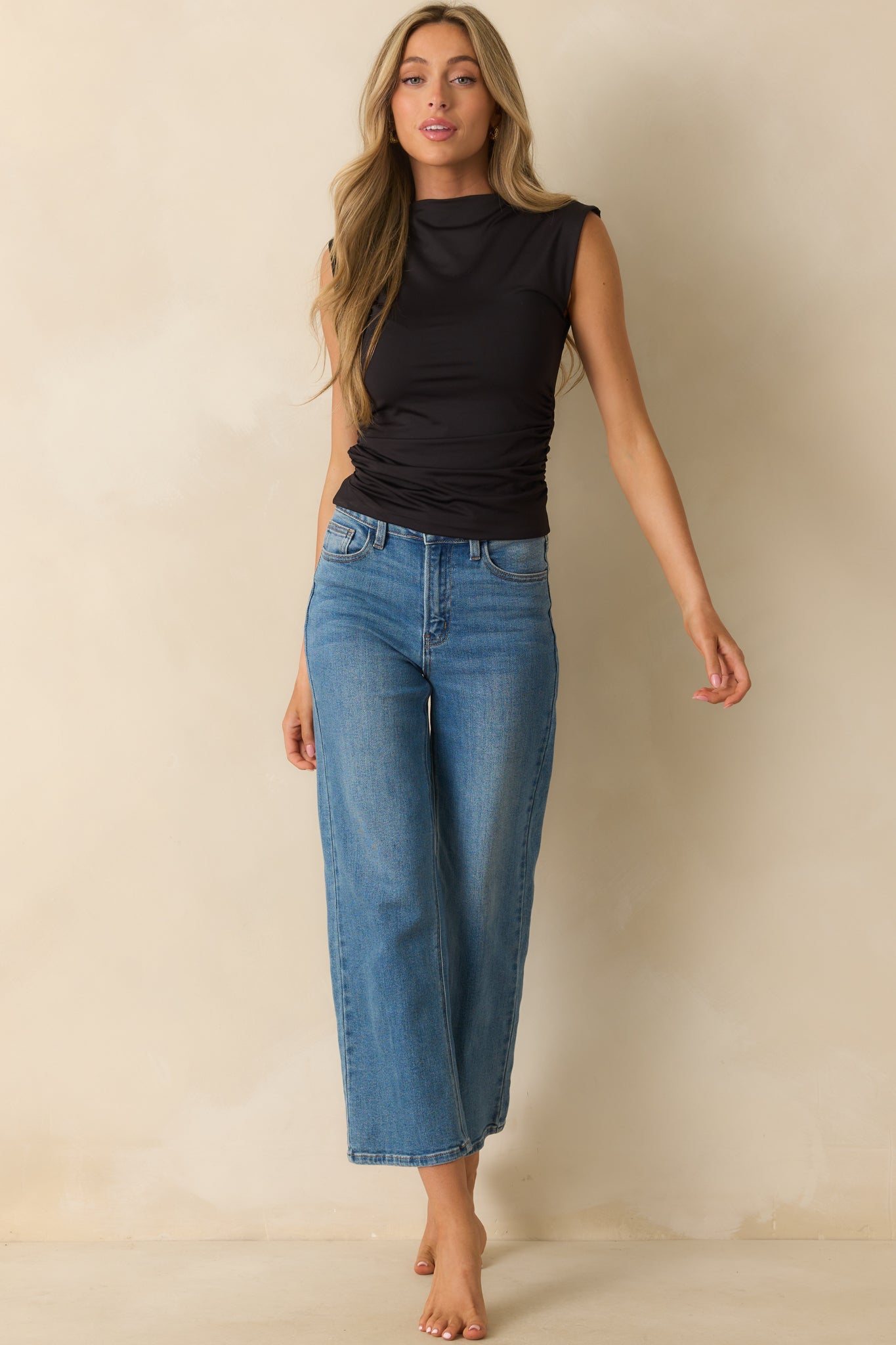 Full-length front view of black mock neck top highlighting stretchy material and ruched sides.