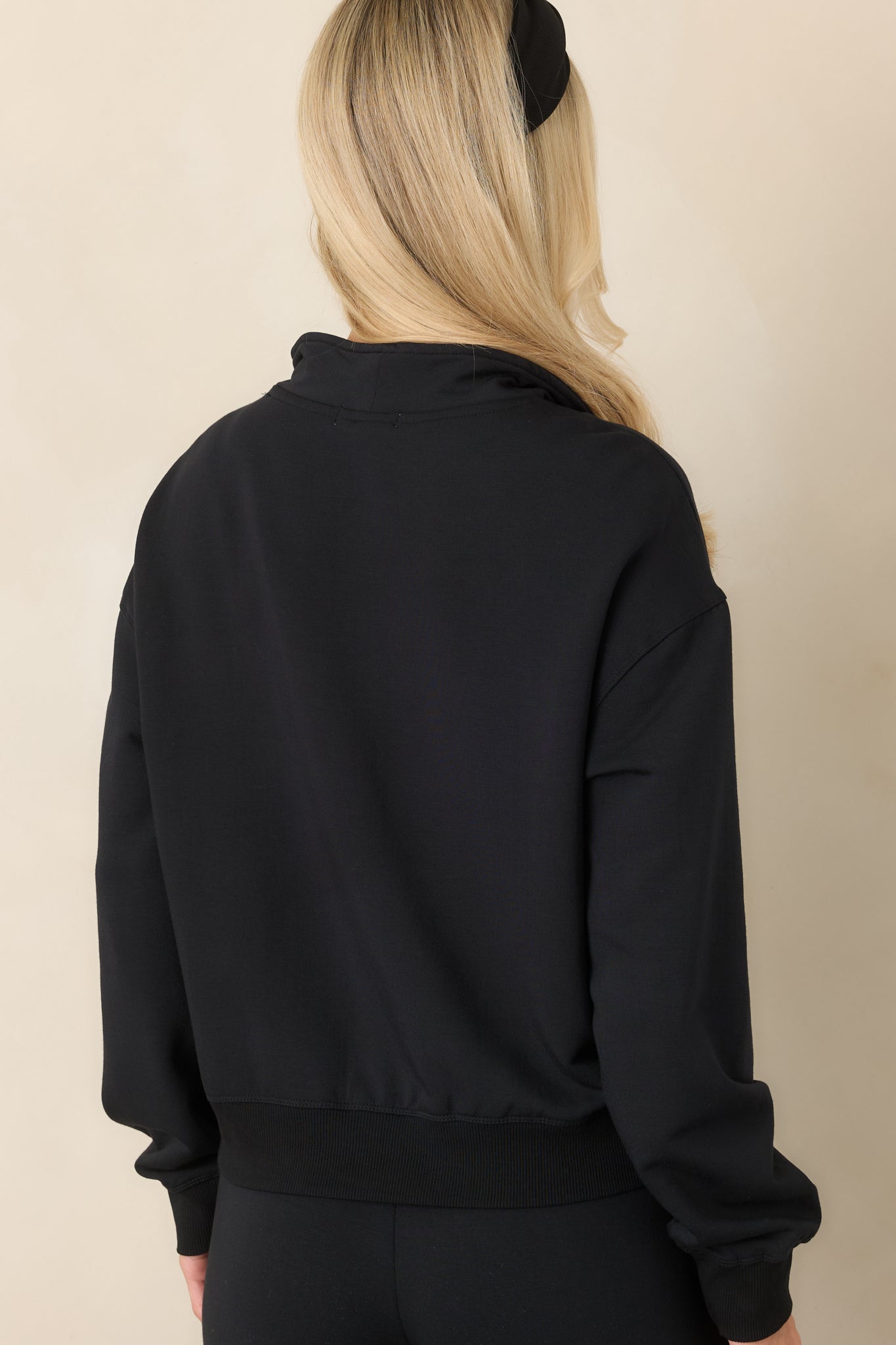 Rear view of the black modal-blend sweatshirt showing its relaxed silhouette, dropped shoulders, long sleeves, and ribbed hem.