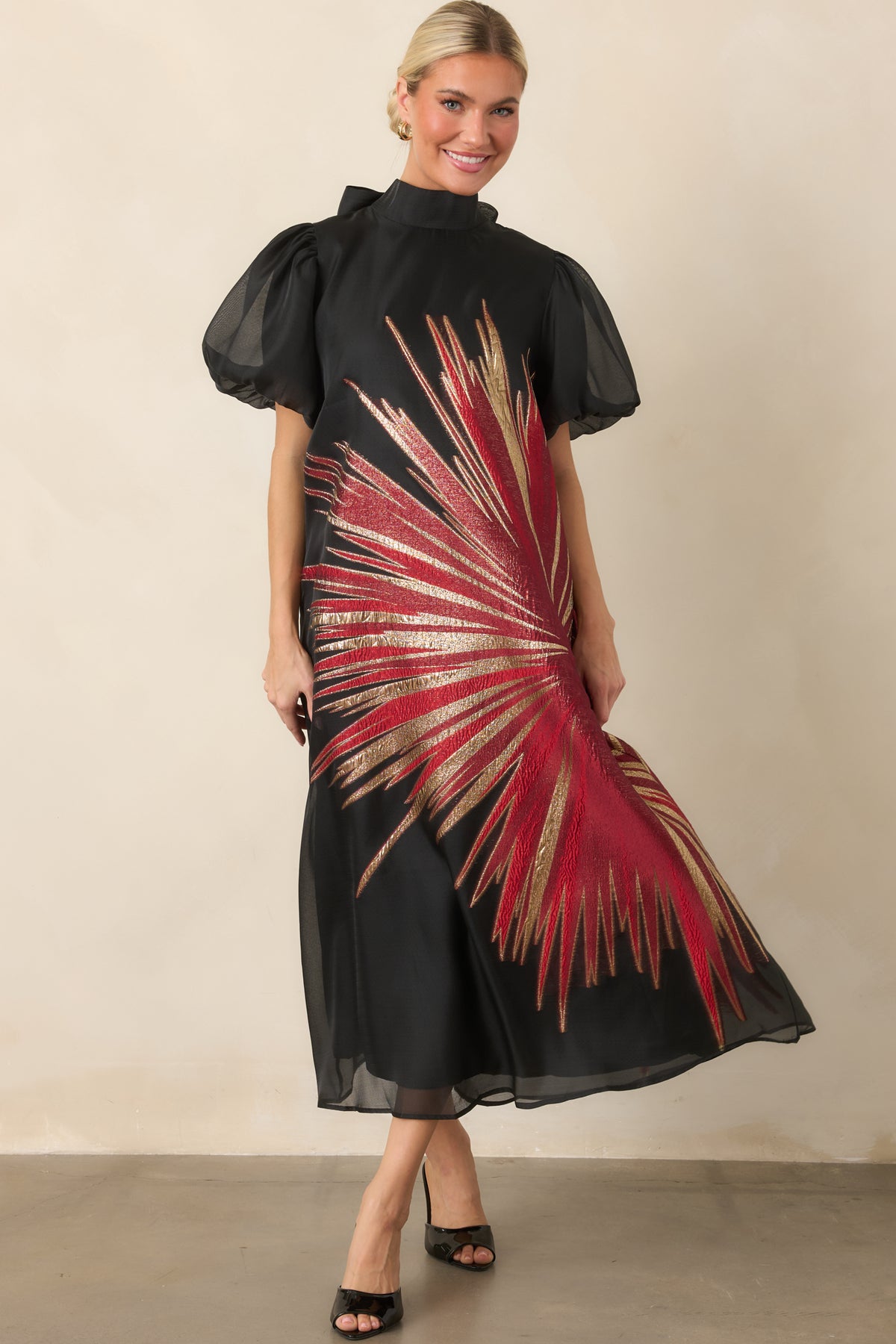 Black overlay dress with an intricate metallic starburst pattern, high neckline, voluminous puff sleeves, and relaxed midi-length shape.