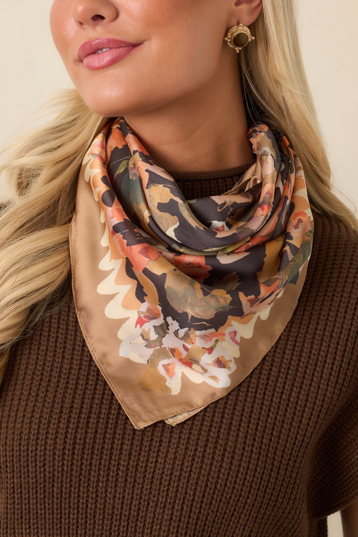 Square scarf featuring a painterly floral print in peach, coral, ivory, olive, and camel against a rich black background.