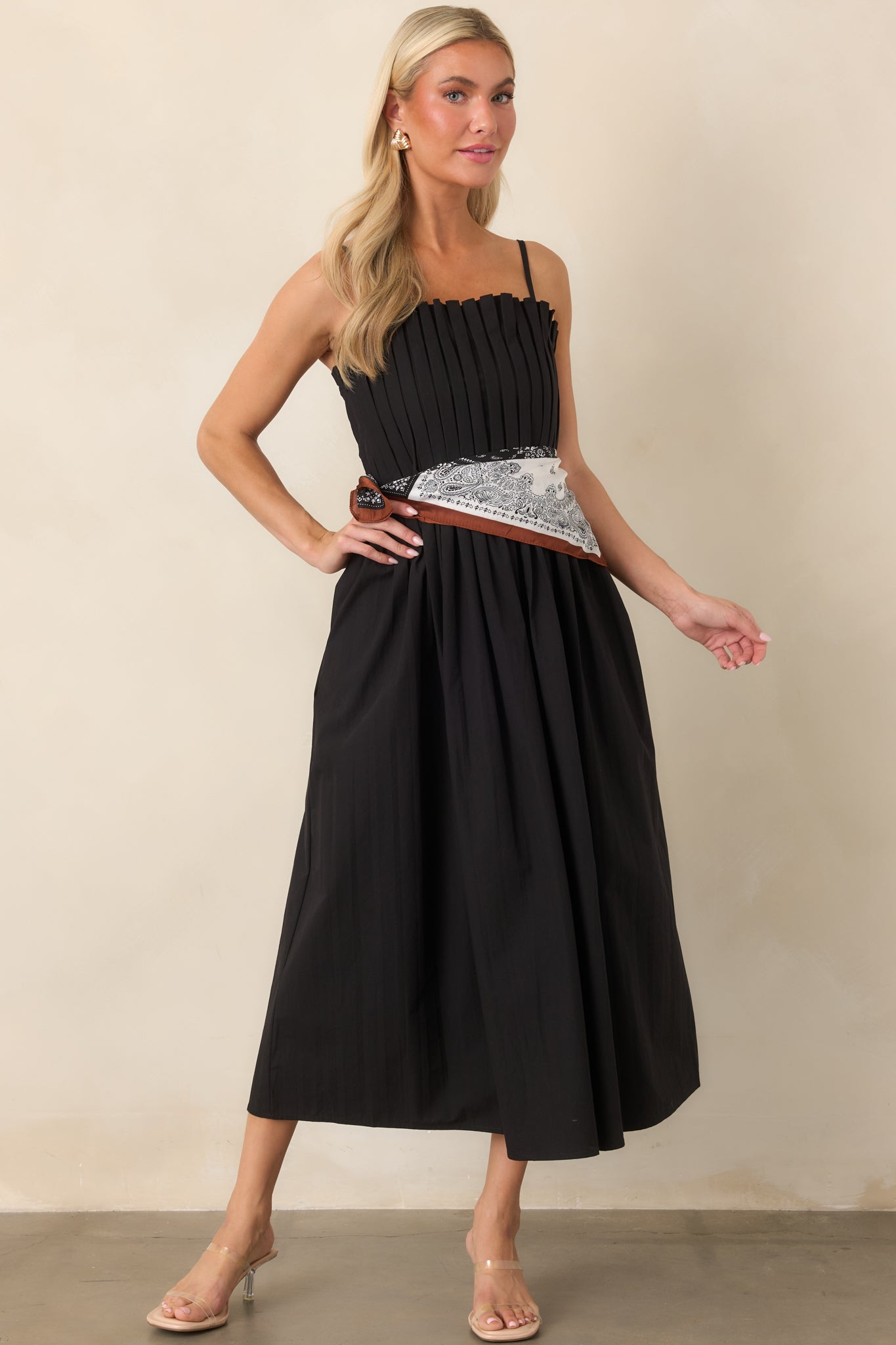 Fitted black midi dress showcasing crisp vertical pleating through the bodice, a gathered waist, and voluminous skirt.