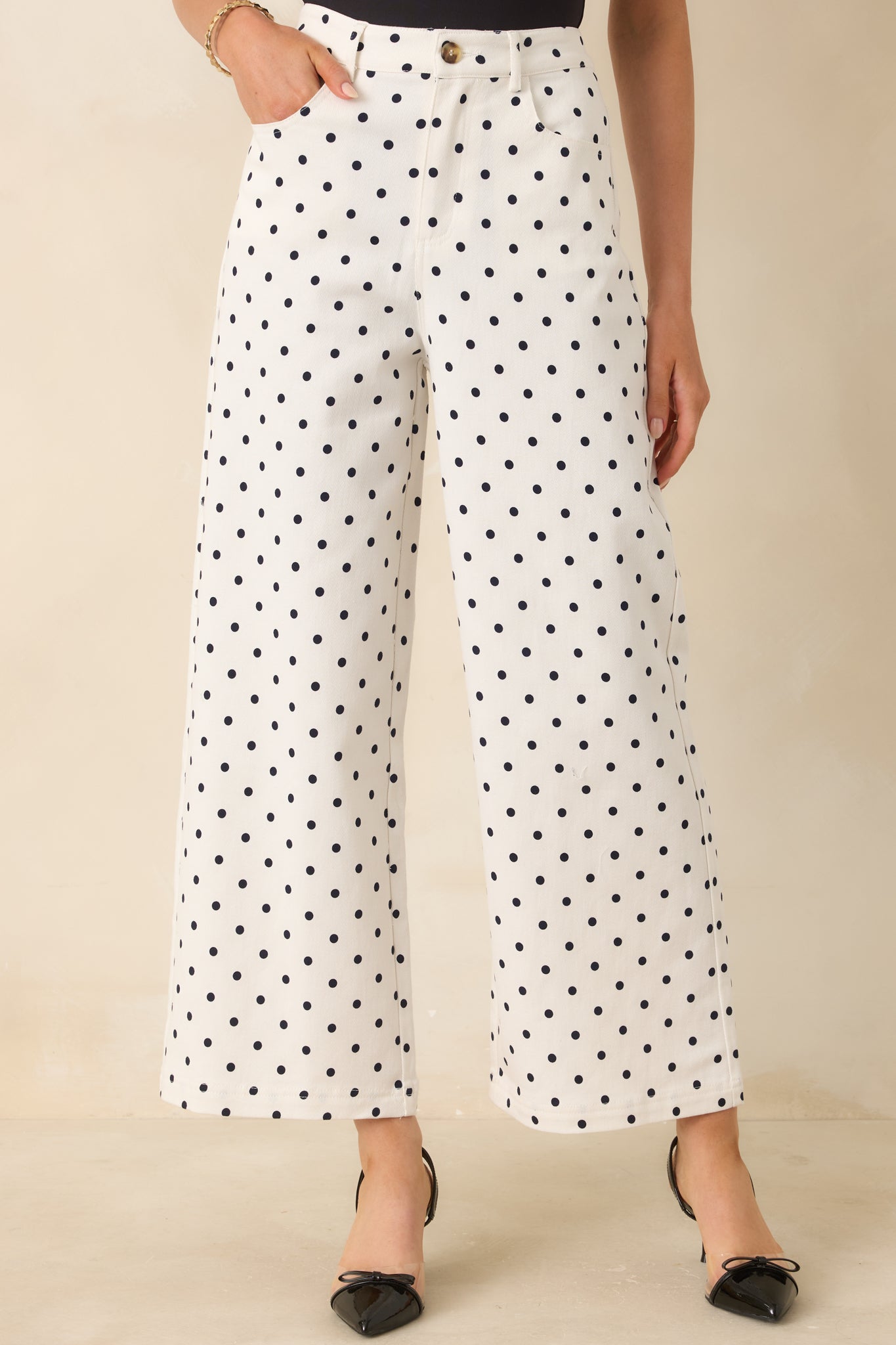 Black polka dot print on ivory cotton fabric with soft texture and structured weave.