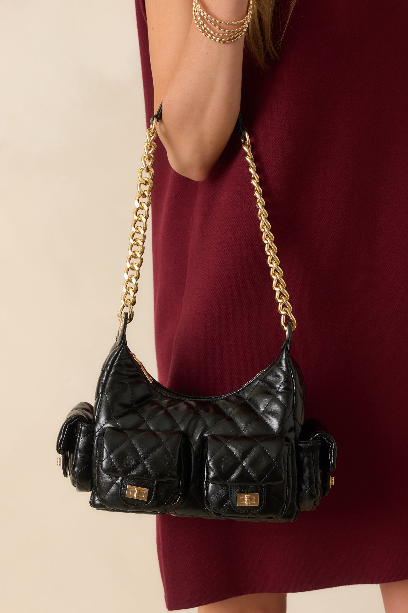 A full view of the black quilted handbag showing the structured silhouette and gold chain shoulder strap.