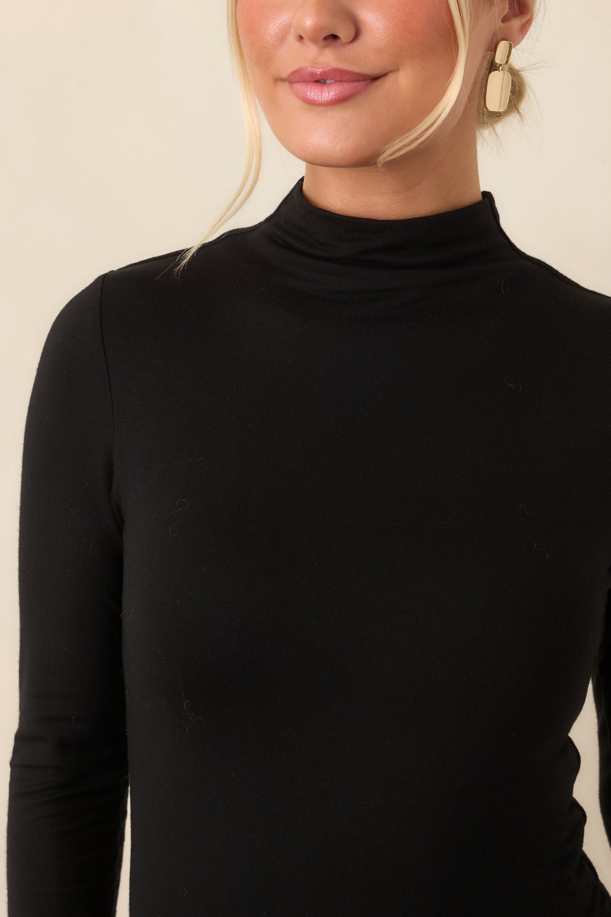 Close-up of the smooth rayon-blend knit texture and clean mock neckline on the black top.
