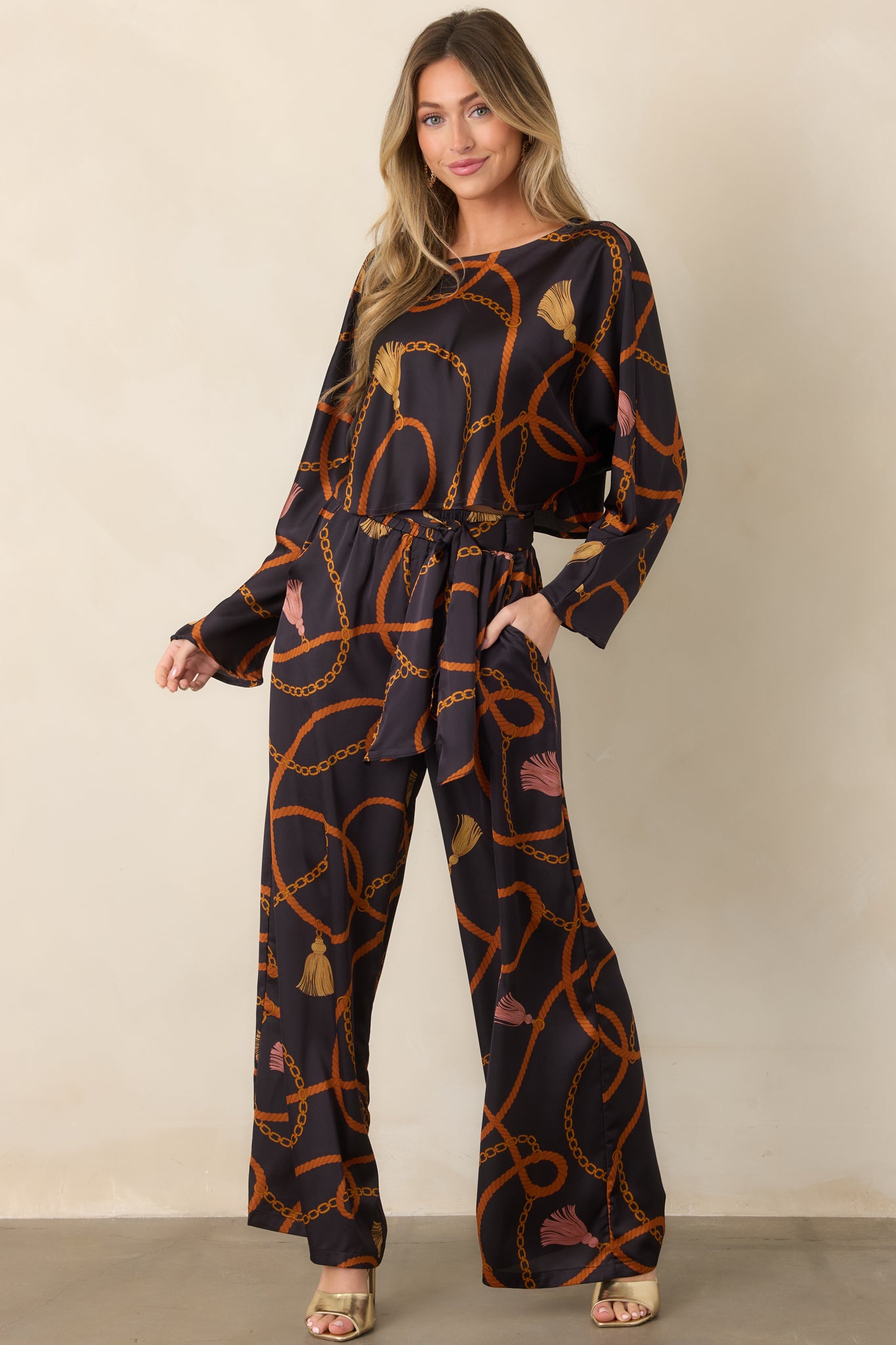 Rich black pants adorned with an ornate rope and chain pattern, featuring a flowing wide-leg shape and polished finish.