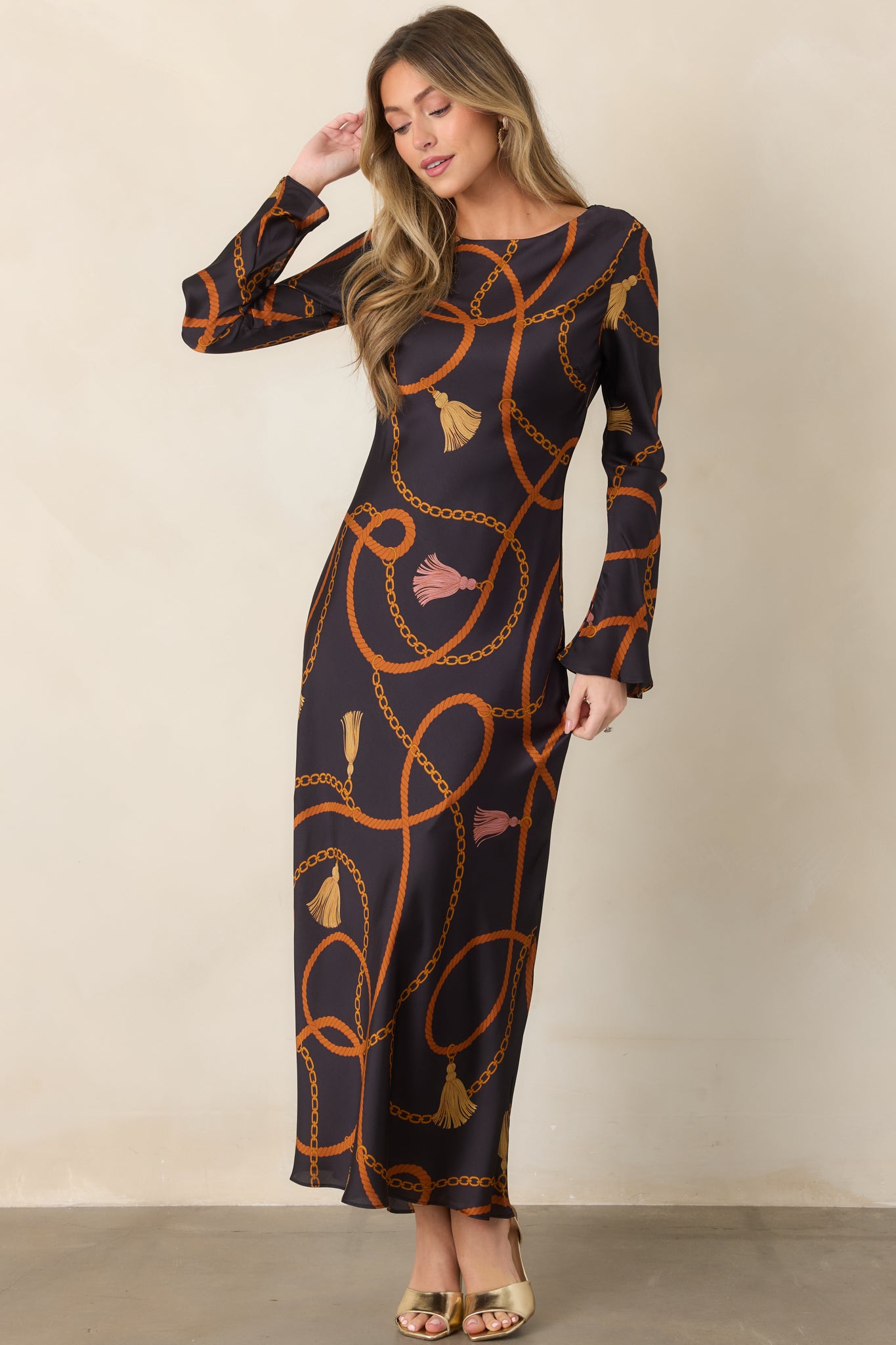 Softly draped black satin maxi dress featuring an intricate equestrian-inspired print and relaxed long-sleeve design.