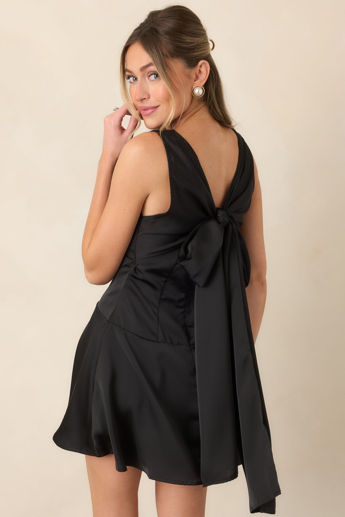 Black satin dress showing its dramatic deep V-back, oversized bow, and concealed zipper closure.