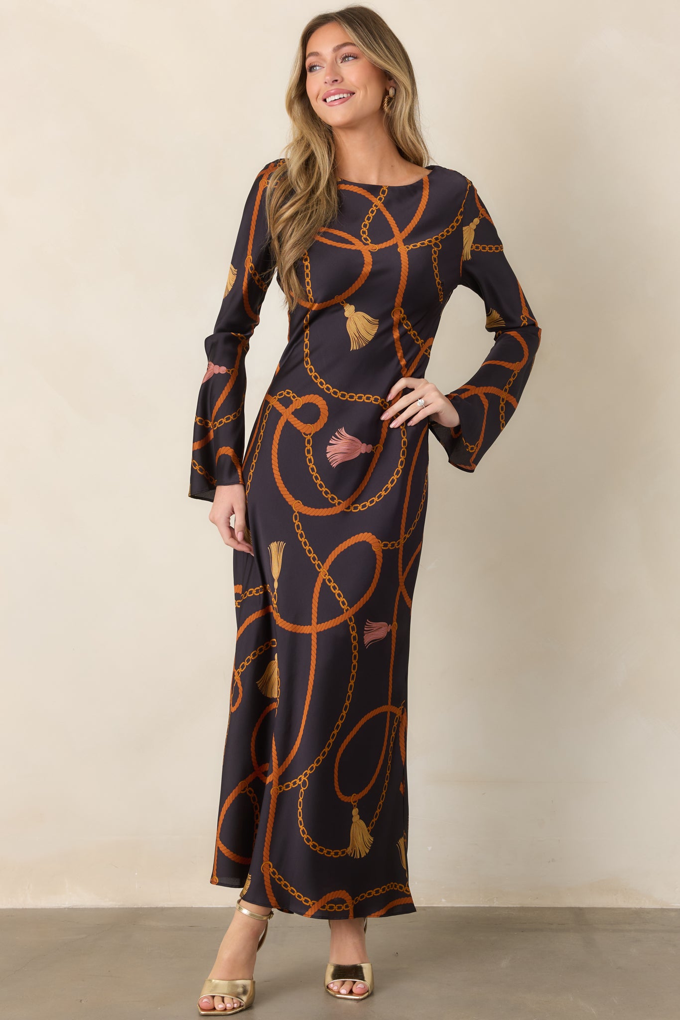 Rich black satin dress highlighting the round neckline, flowing long sleeves, and elegant floor-length silhouette.
