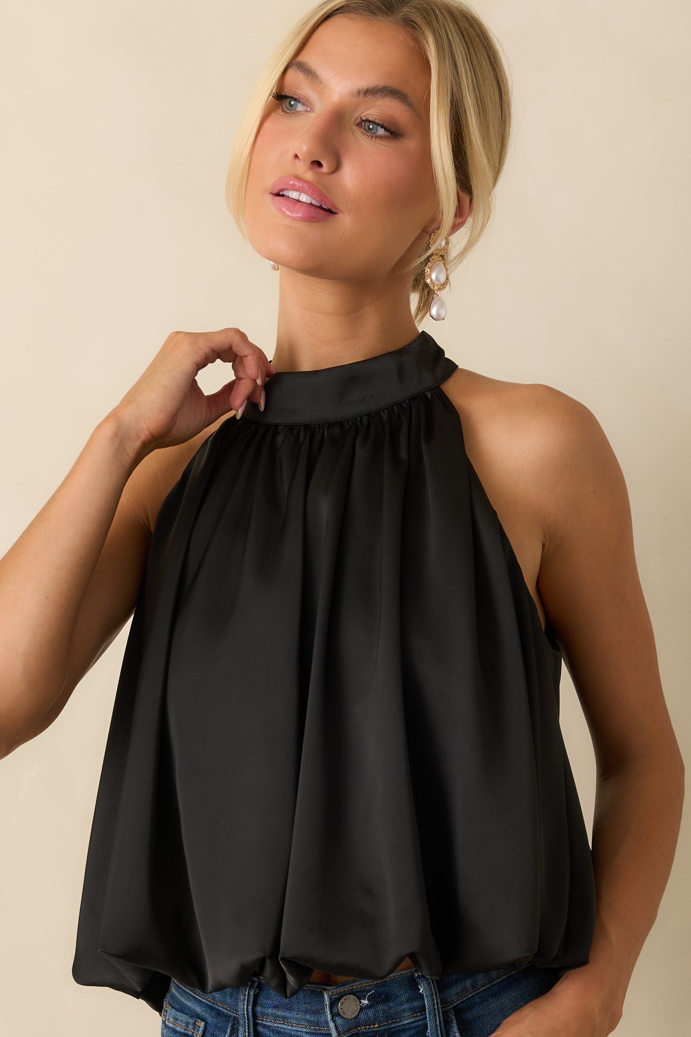 Black halter top emphasizing the elegant curve of the neckline and fluid satin texture.