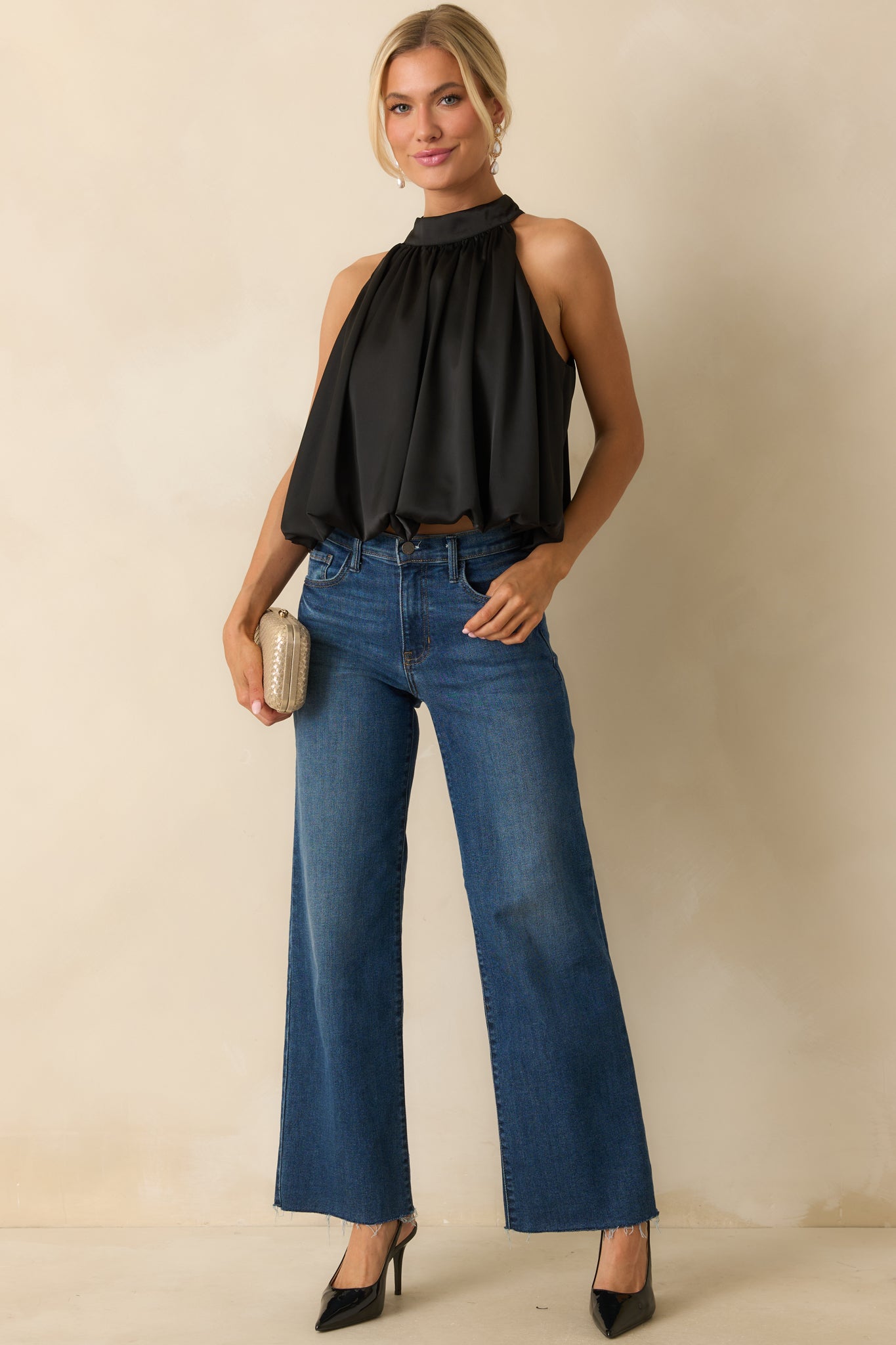 Black halter top styled to highlight its fluid satin fabric and elegant gathered neckline.