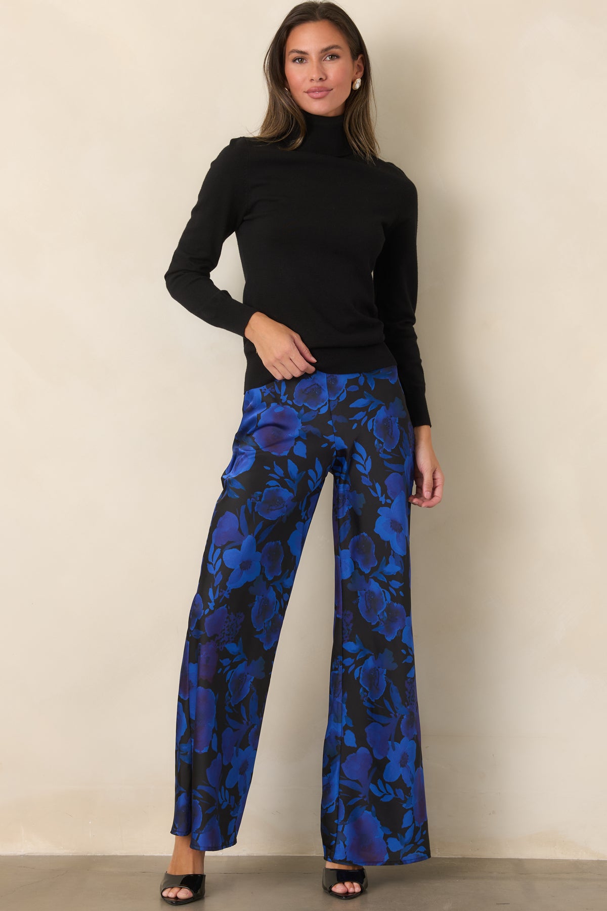 Black satin pants with a bold cobalt and violet floral print, high-rise waist, and flowing wide-leg silhouette.