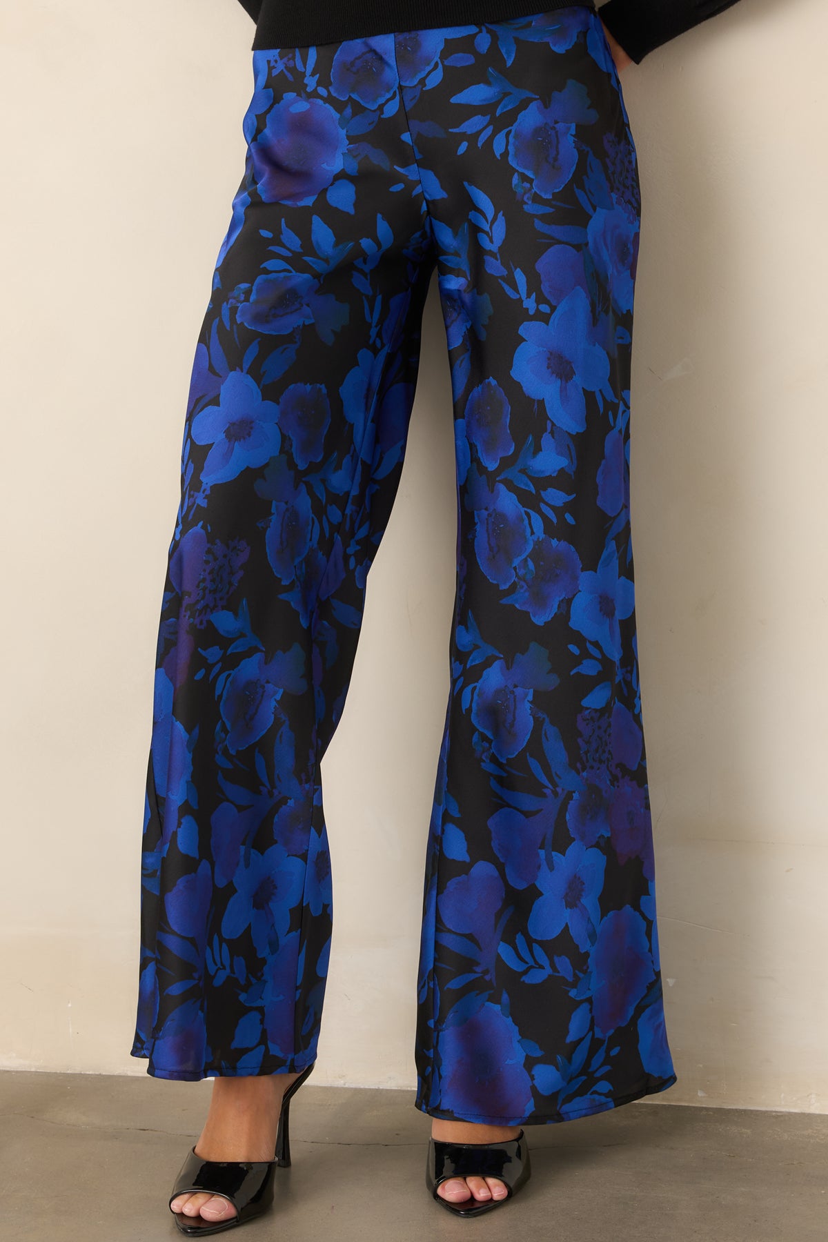 Black satin pants showcasing the clean flat-front waistband and bold floral print in cobalt and violet.