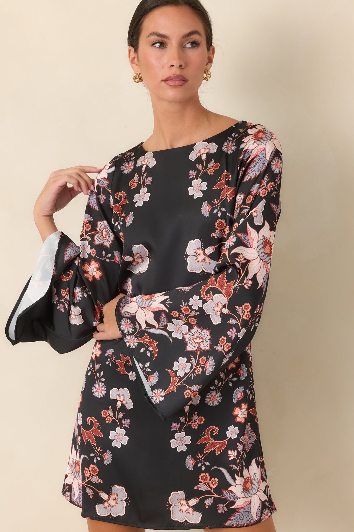 Black satin mini dress showcasing periwinkle blooms and the relaxed shift silhouette.
