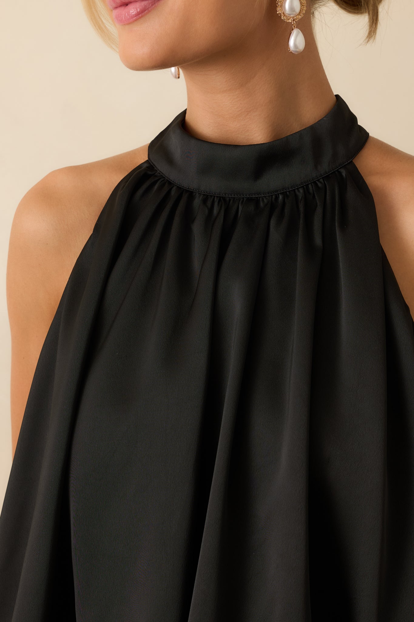 Close-up of the black satin fabric highlighting its gathered neckline and lustrous finish.